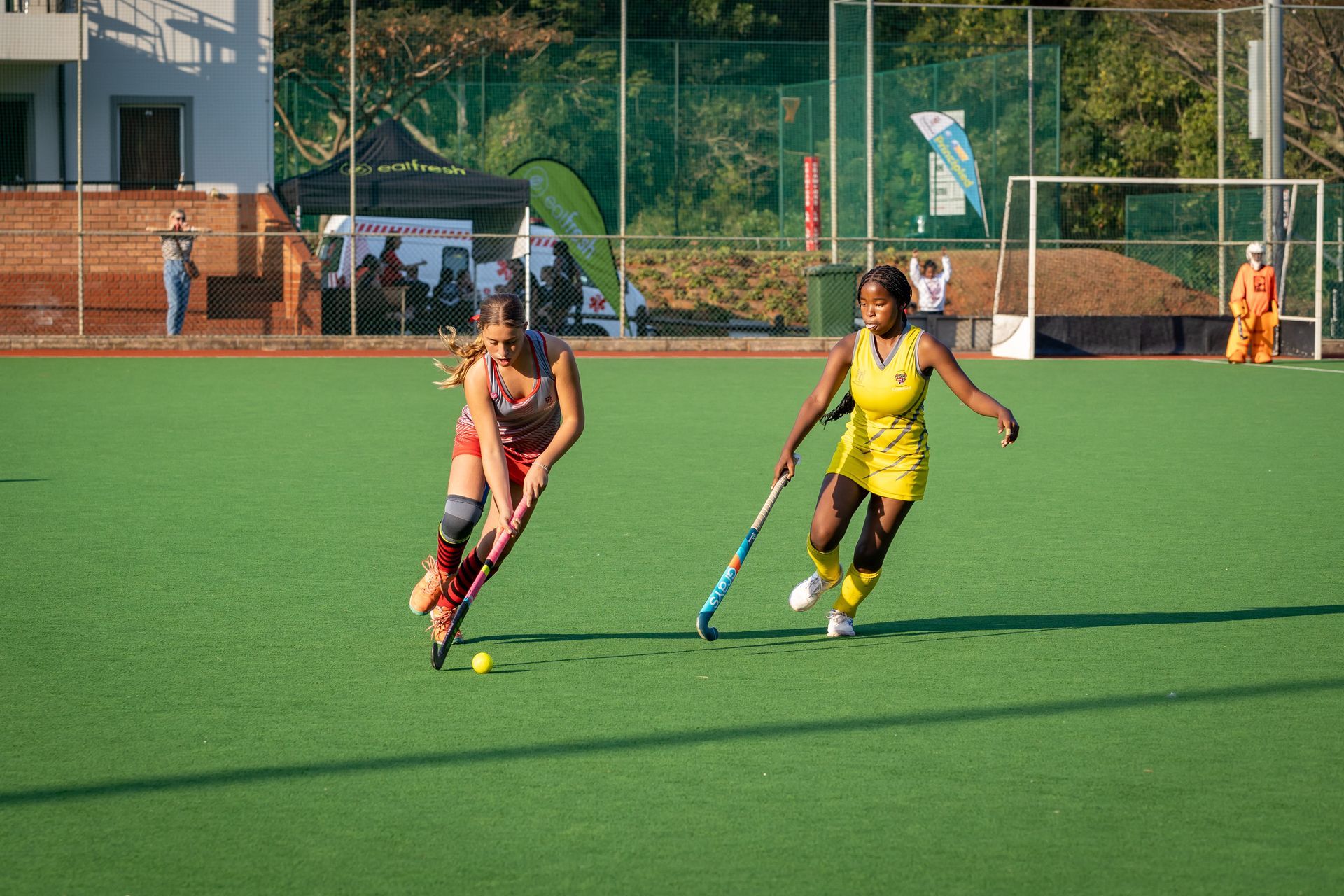 Two women are playing field hockey on a field.