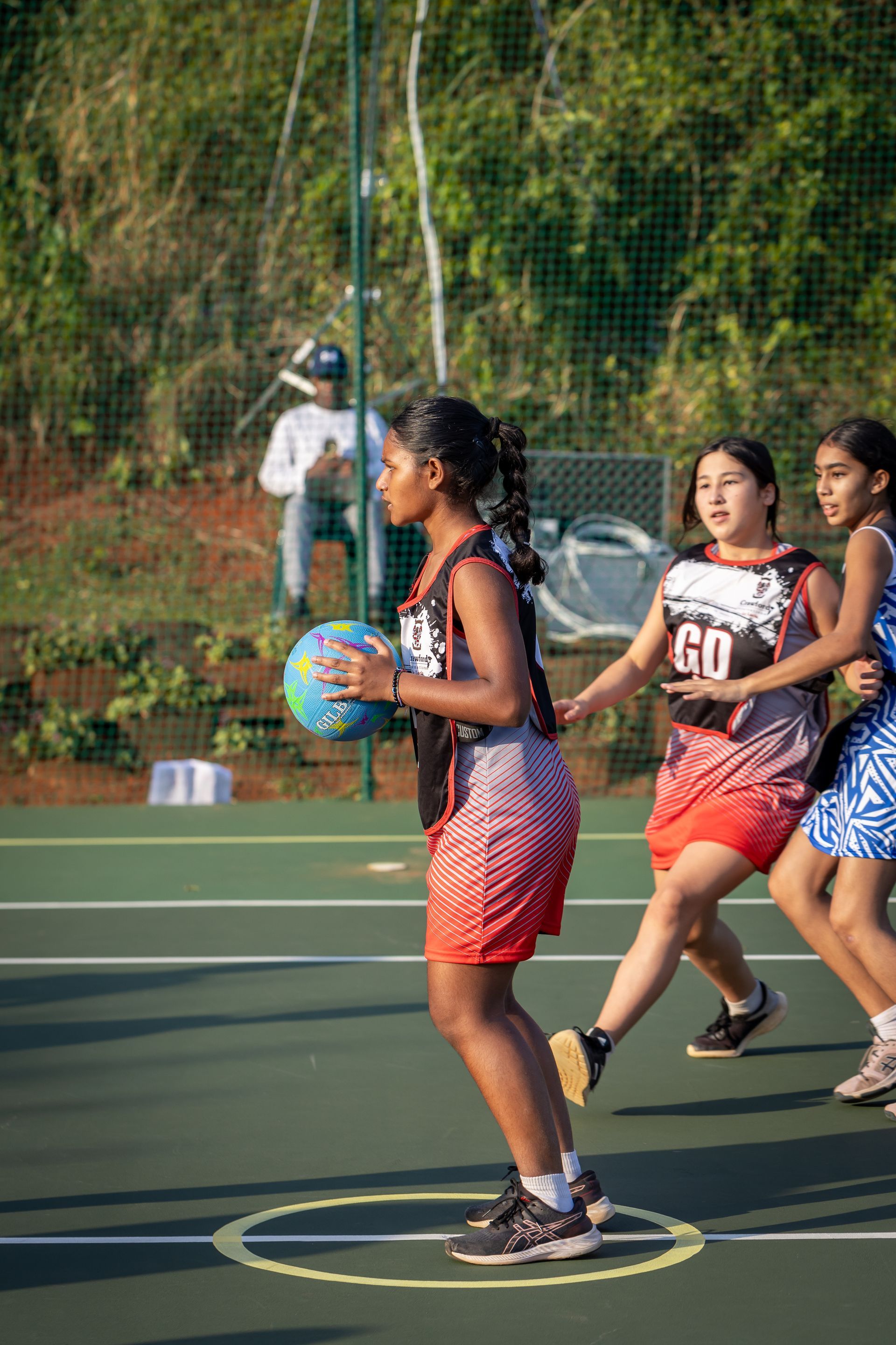 A group of young girls are playing netball on a court.