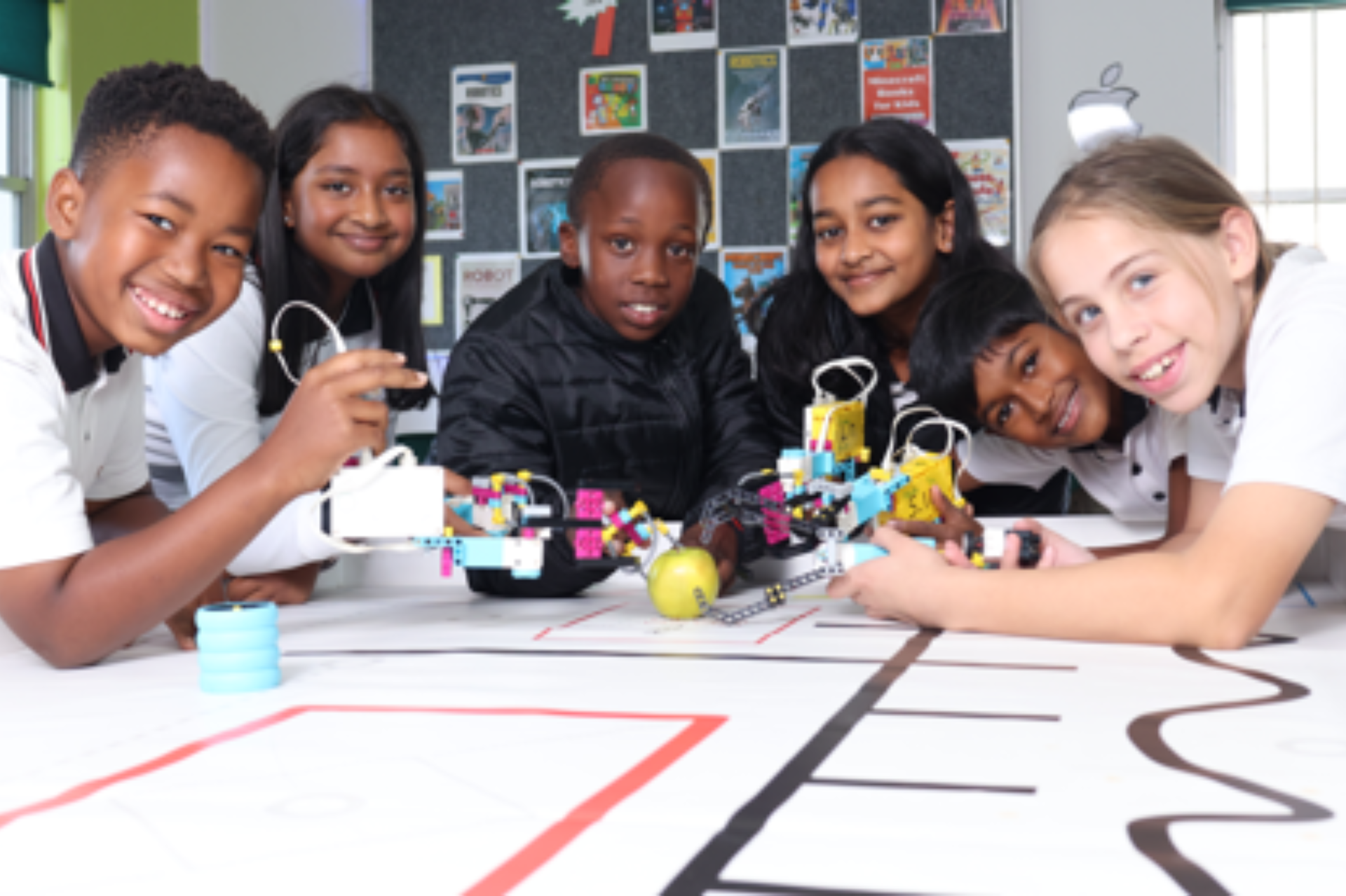 A blue robot with the letter m on it is sitting on a table.