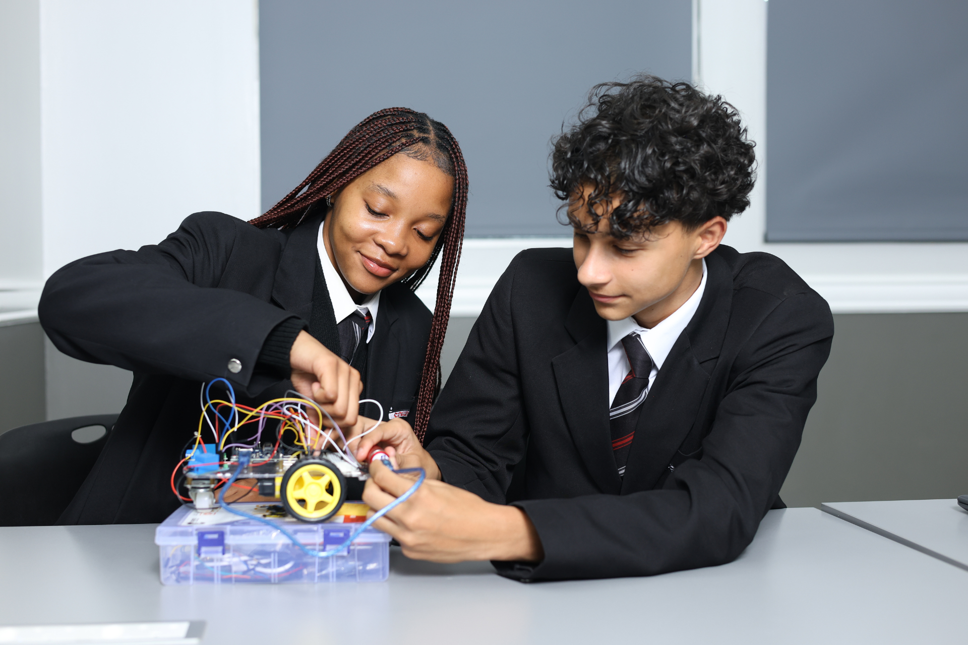 a blue robot with the letter m on it is sitting on a table .