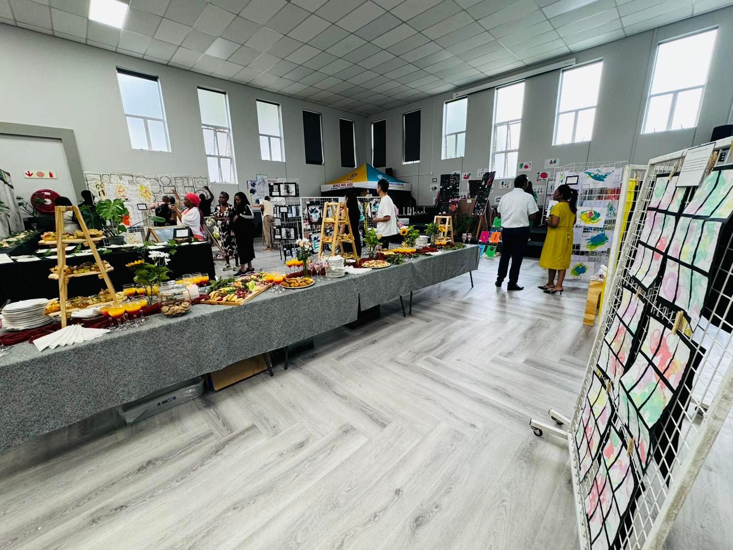 A large room filled with tables and people standing around them.