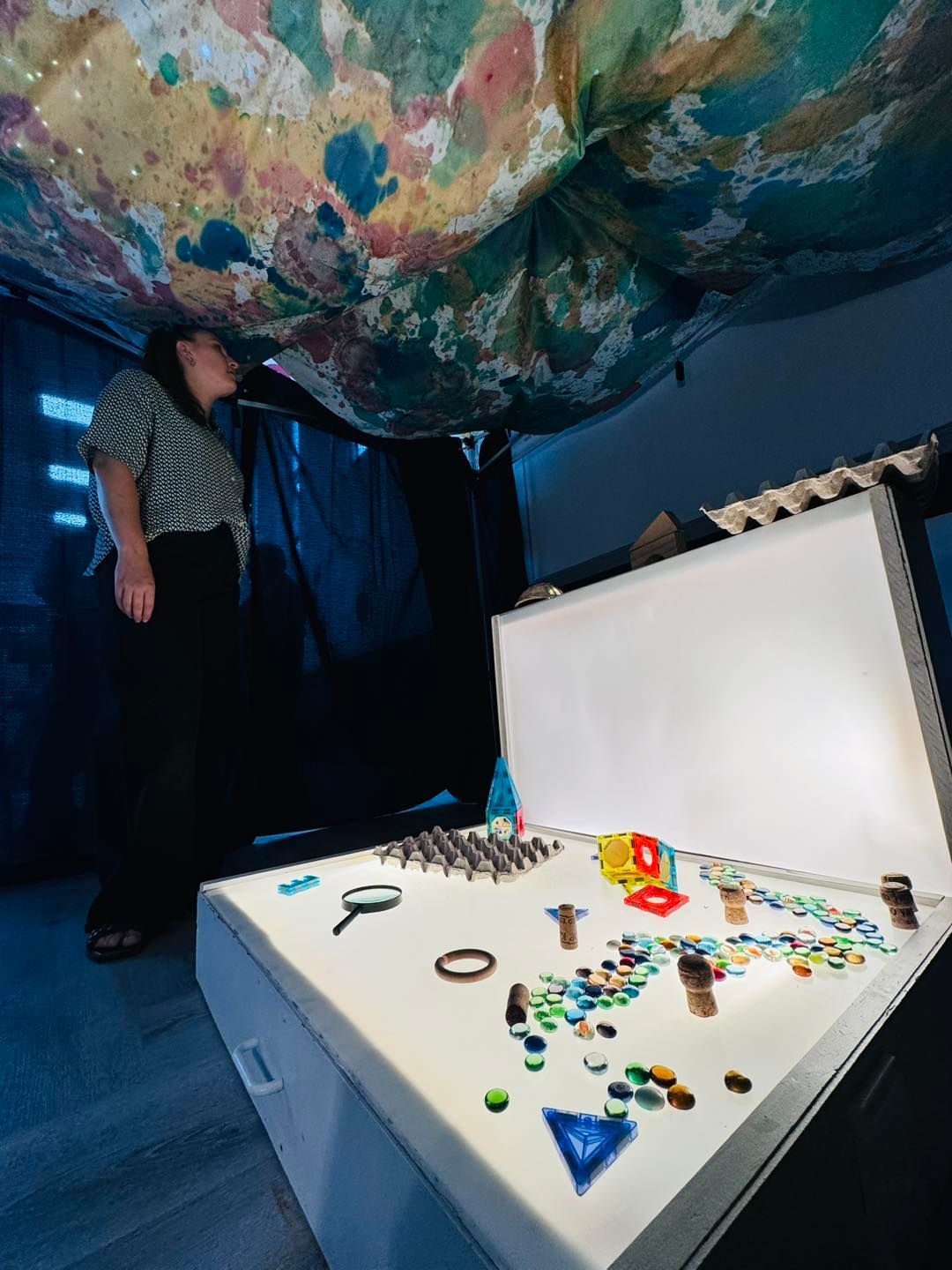 A woman standing next to a table with a painting on it