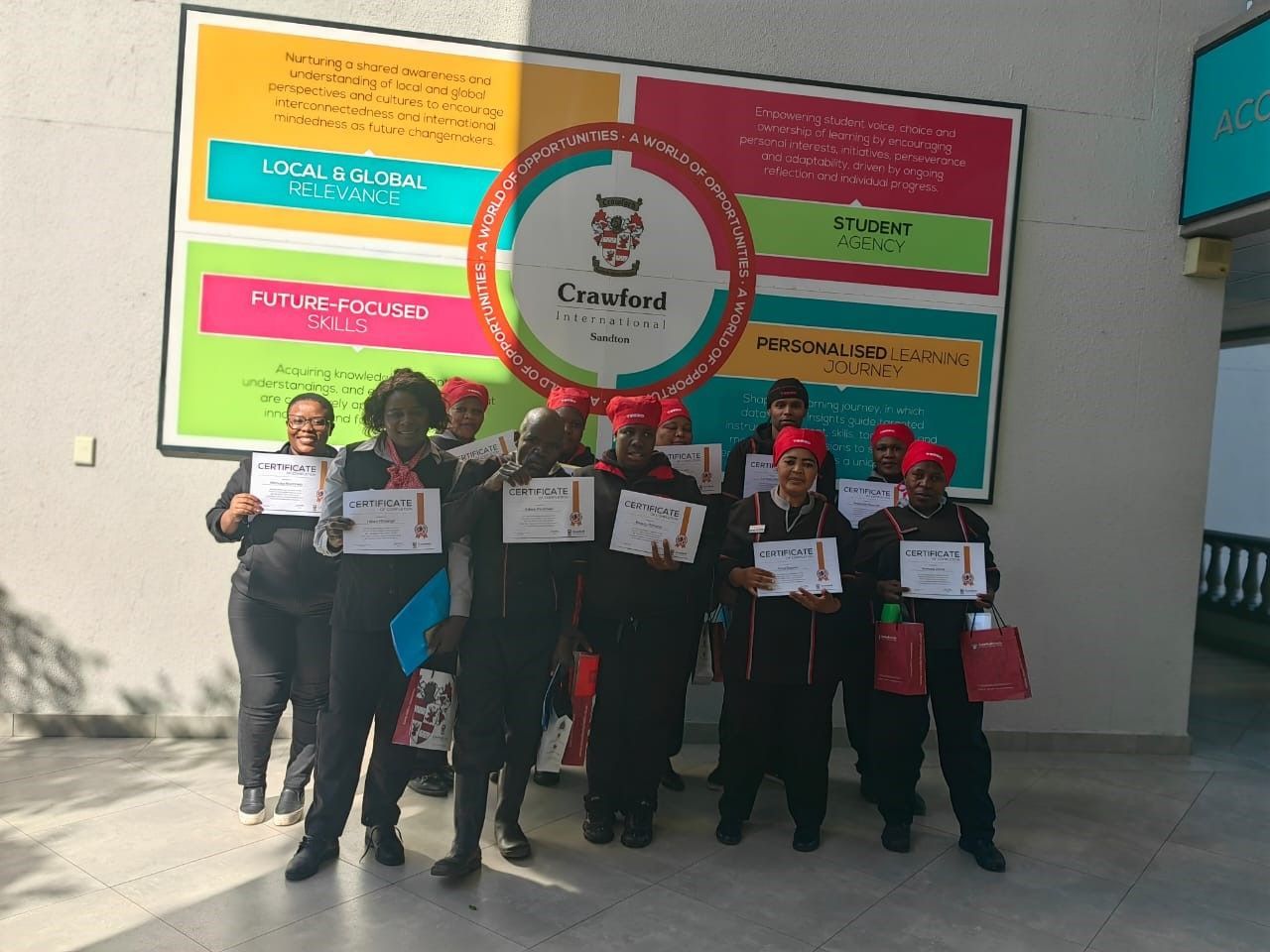 A group of people standing in front of a wall holding certificates.