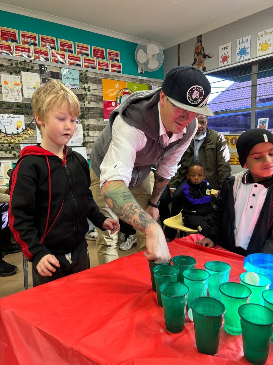 A man is standing next to a table with green cups on it.