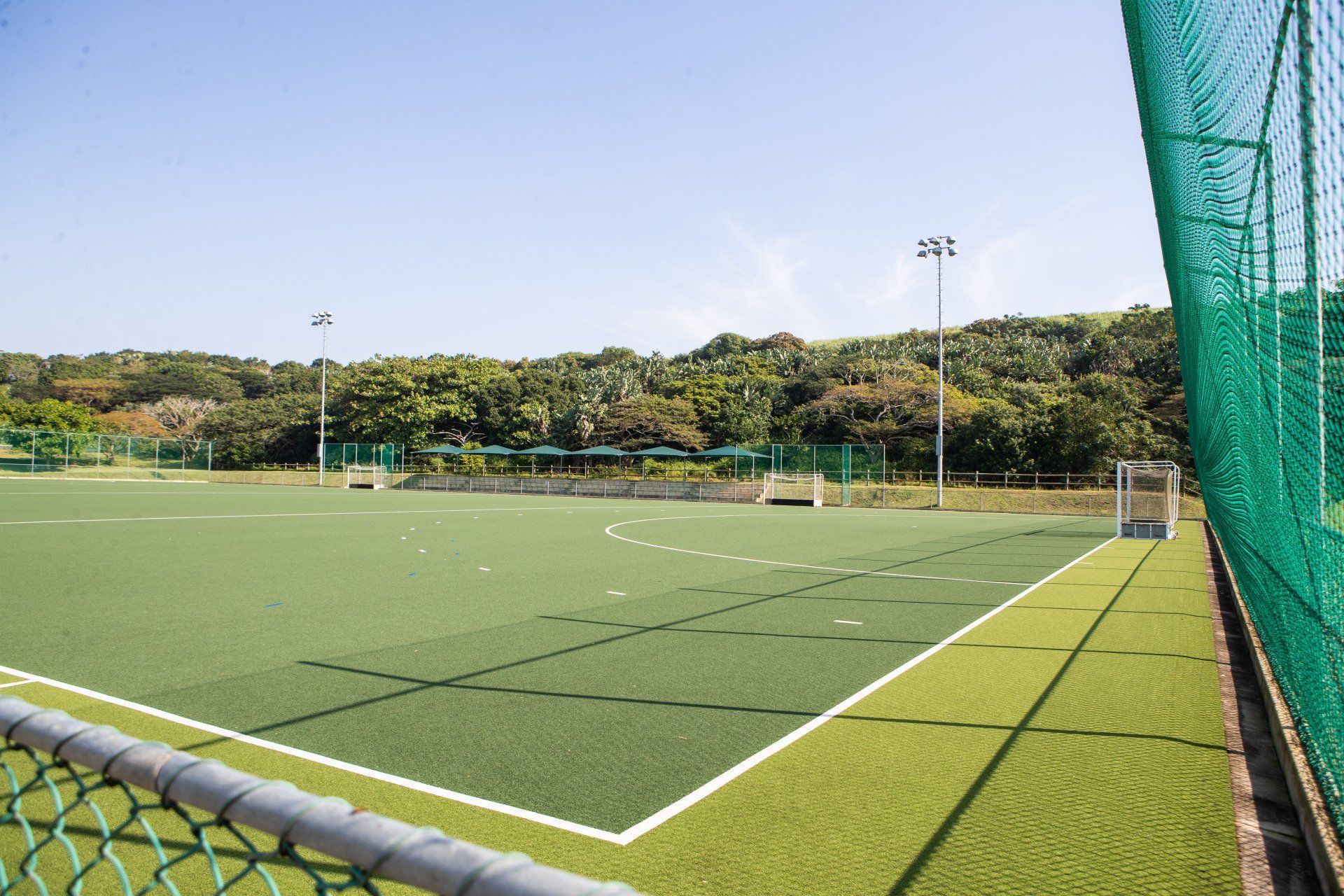 a sport field with a fence around it and trees in the background .