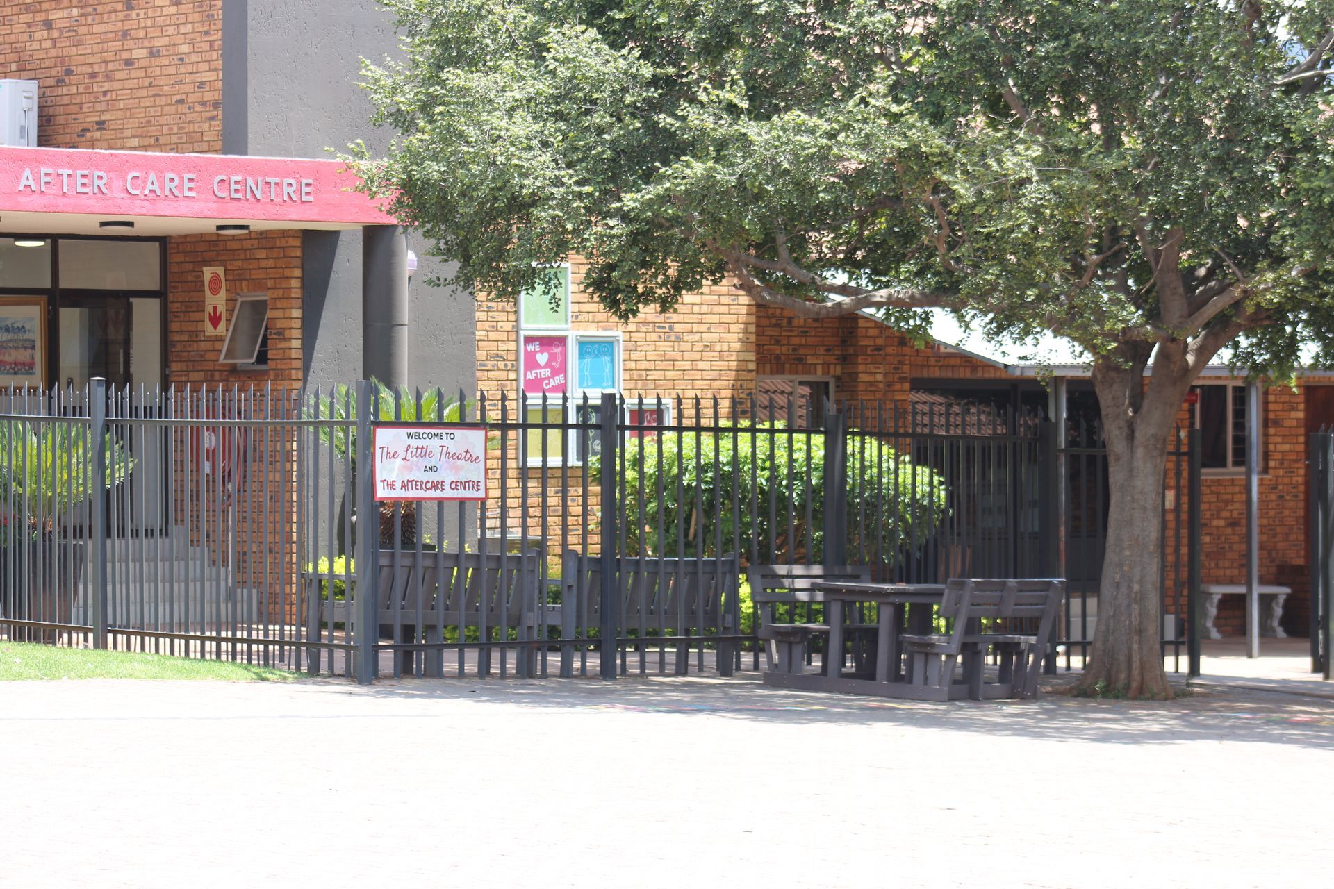 a brick building with a red awning is surrounded by trees and bushes .