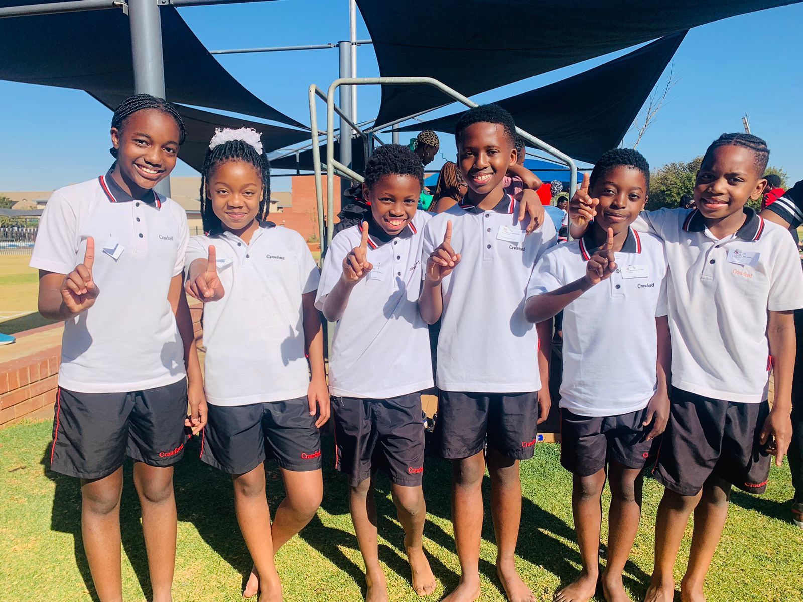 A group of children are posing for a picture and giving a peace sign.