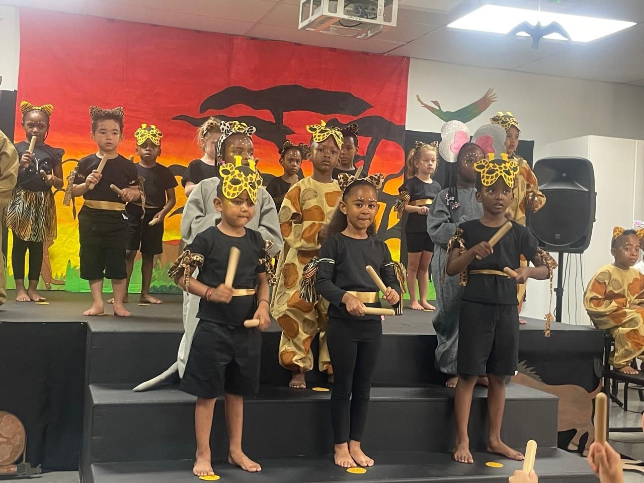 A group of children are standing on a stage playing instruments.