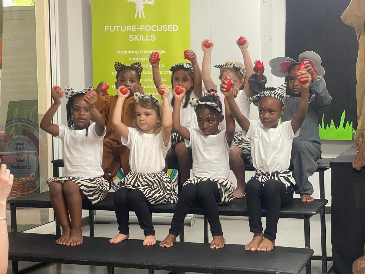 A group of children are sitting on a bench holding dumbbells in their hands.