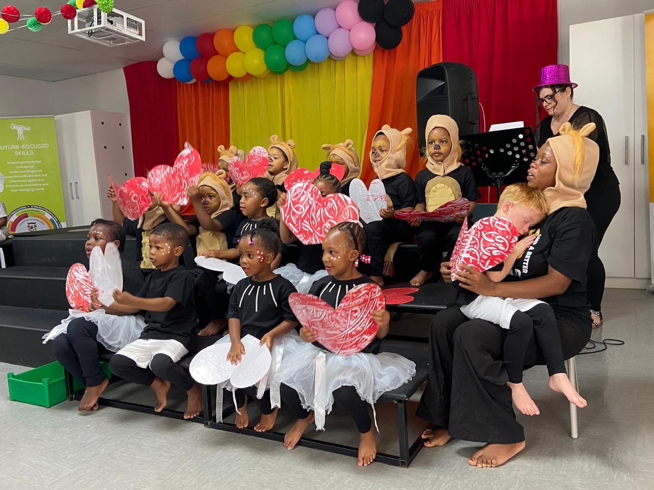 A group of children dressed in costumes are sitting on a stage.