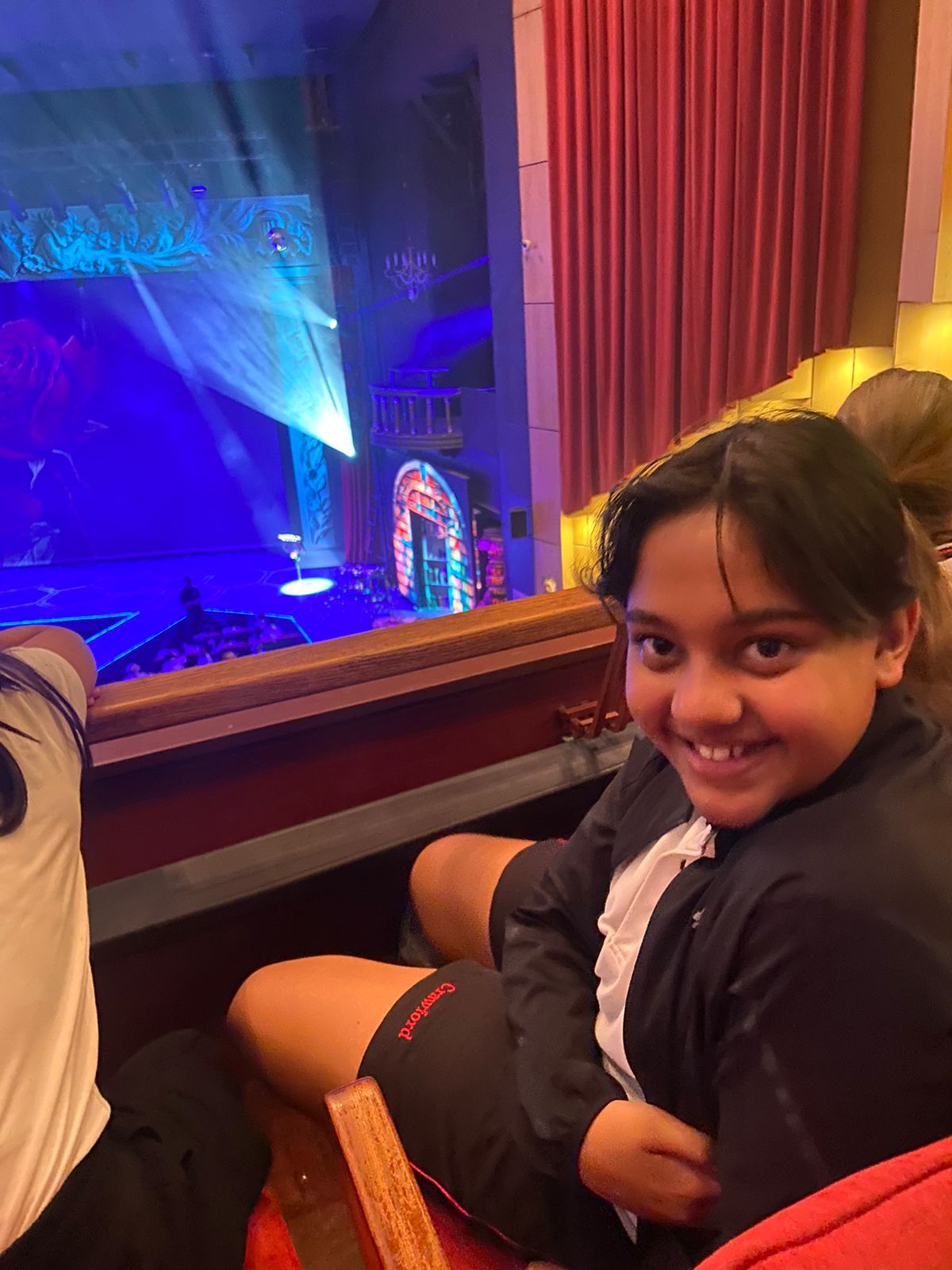A young girl is sitting in a theater watching a show.