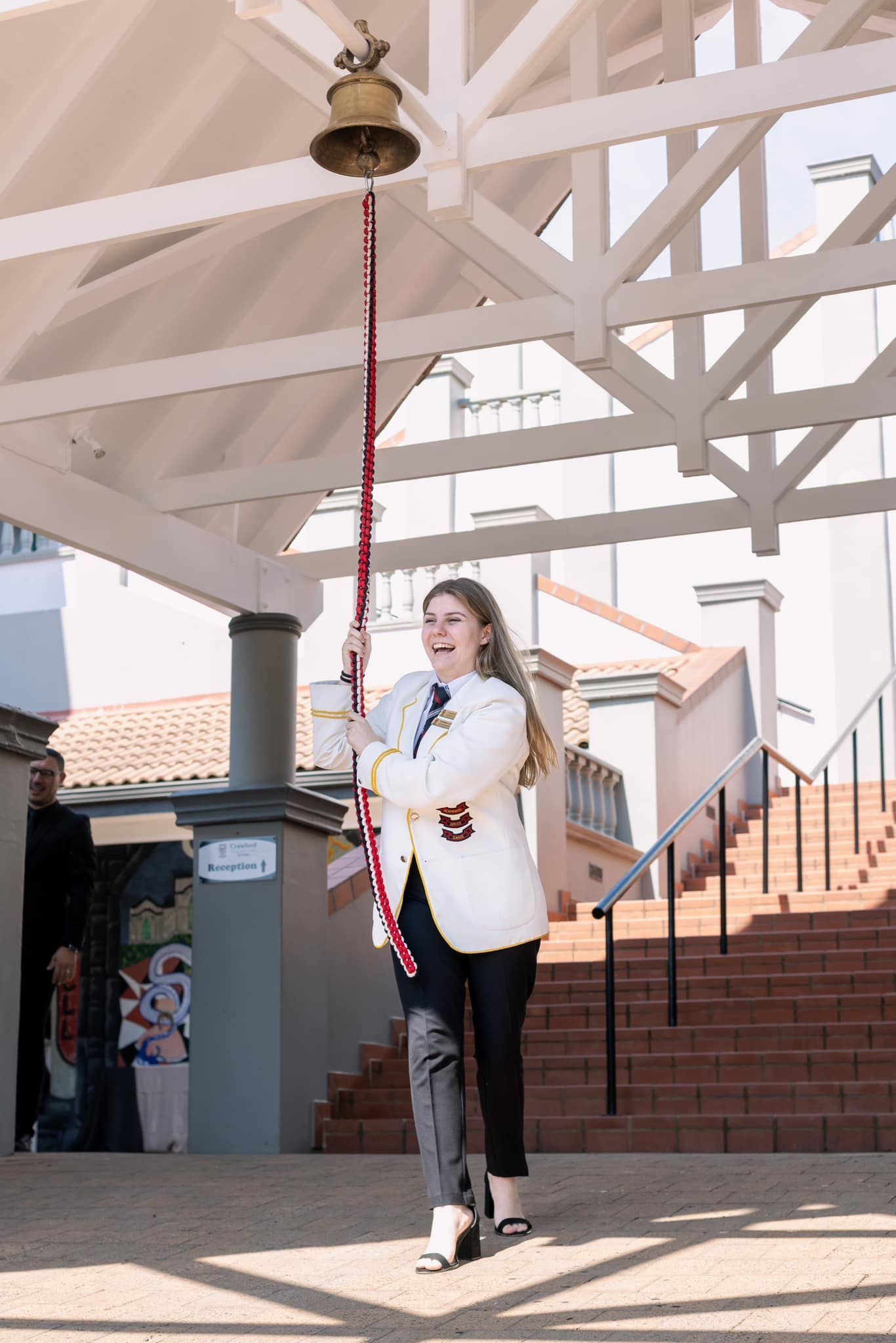 A woman is holding a bell hanging from the ceiling.