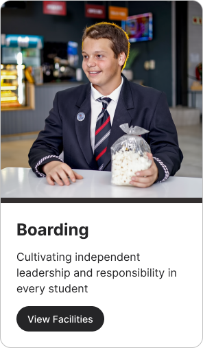Boy in school uniform holding popcorn; cafeteria setting. 