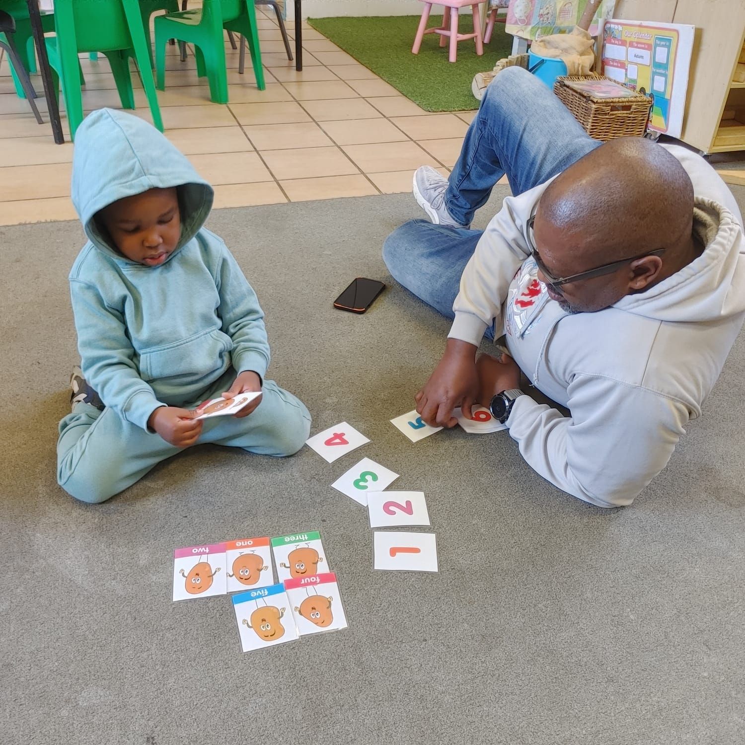 A man and a child are playing cards on the floor