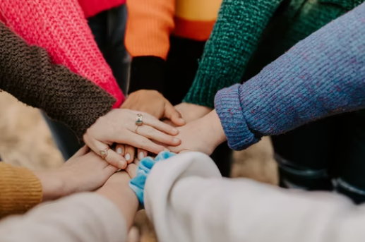 Many hands gathered in the centre of circle, surrounding yourself with the right people