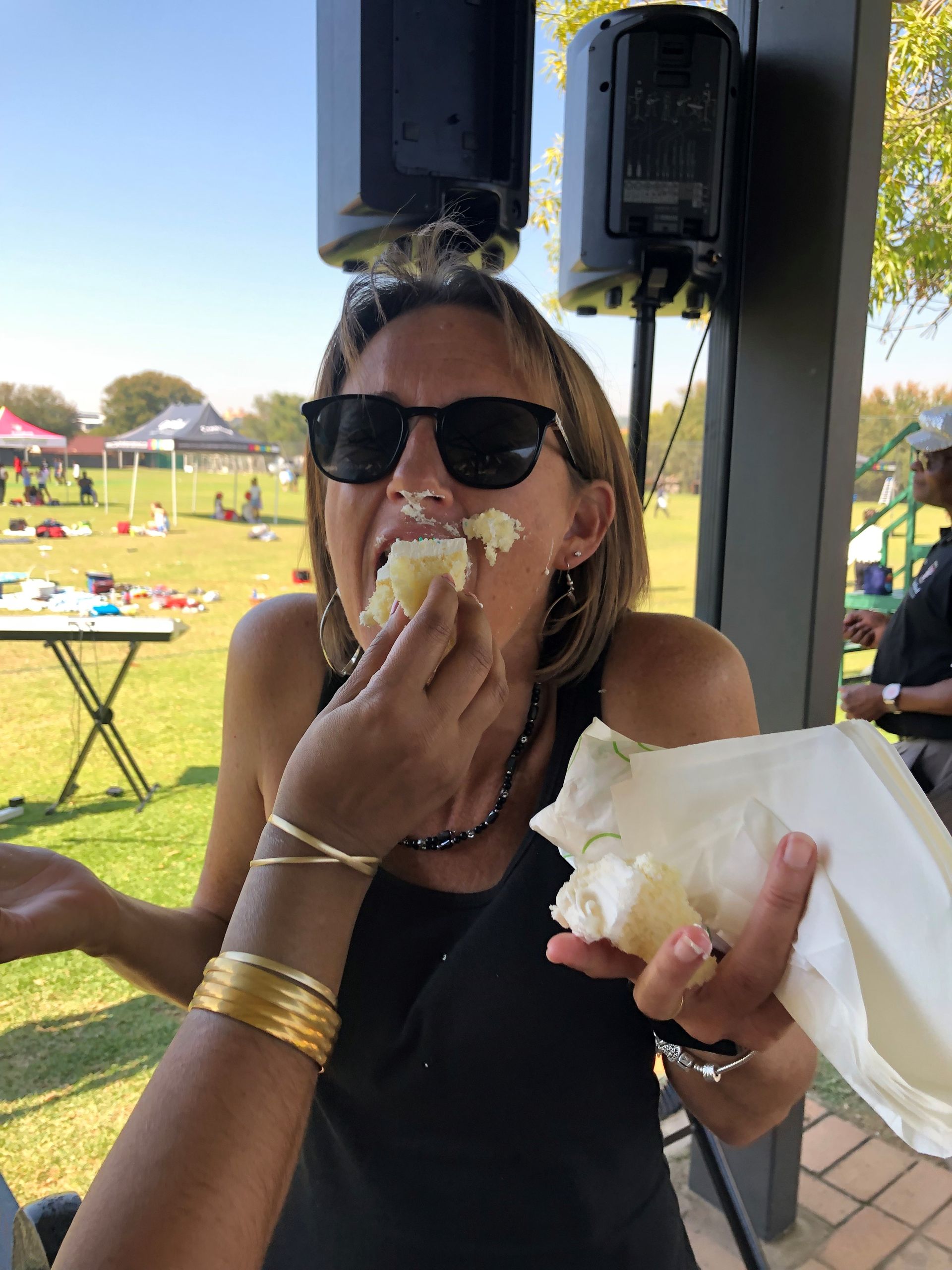 A woman wearing sunglasses is eating a piece of food.