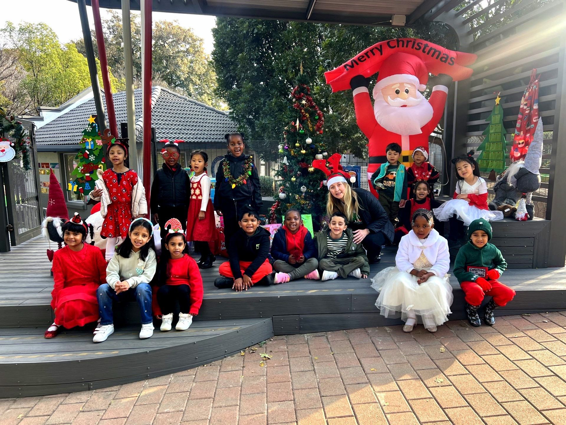 Children in holiday attire posing near Christmas decorations.