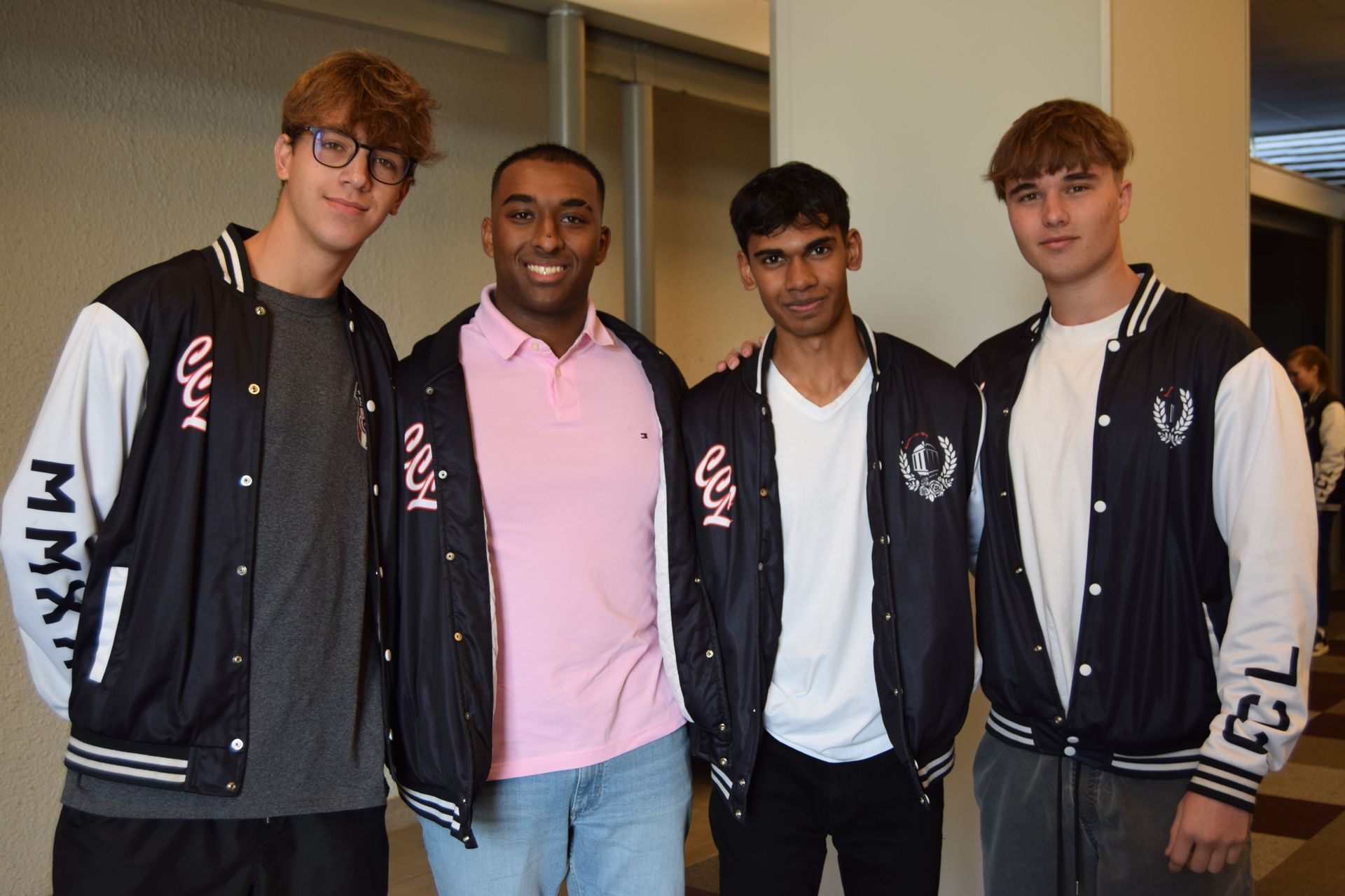 A group of young men wearing varsity jackets are posing for a picture.