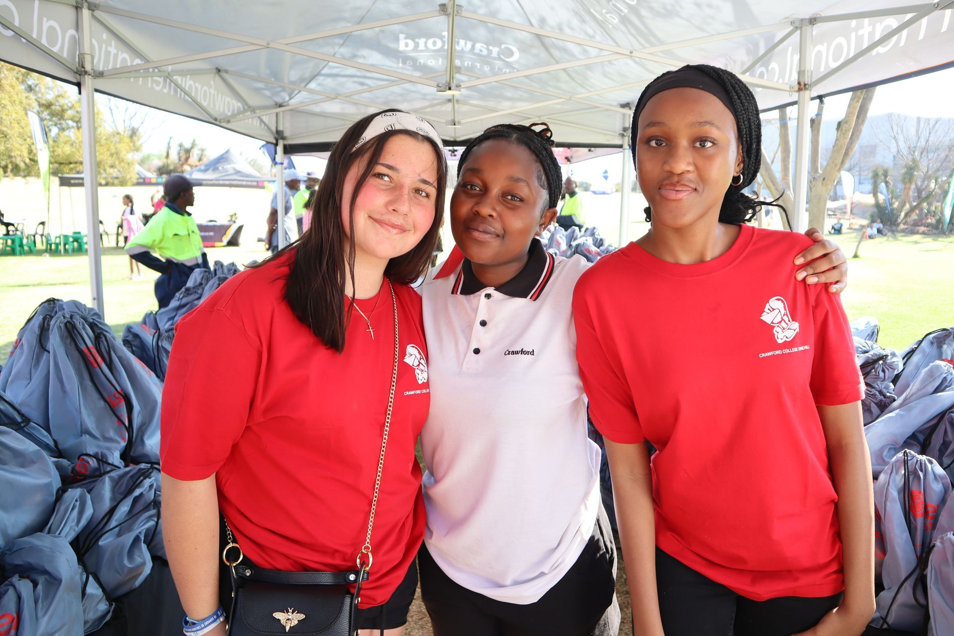 Three young women are posing for a picture under a tent.