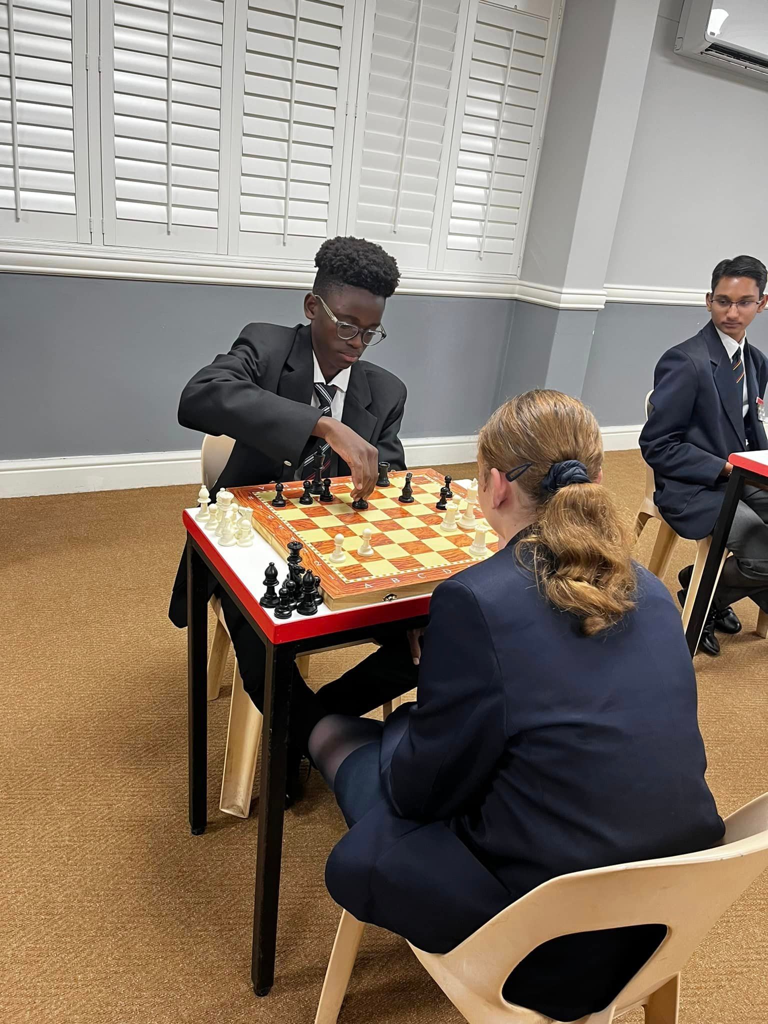 A group of people are playing chess in a room.