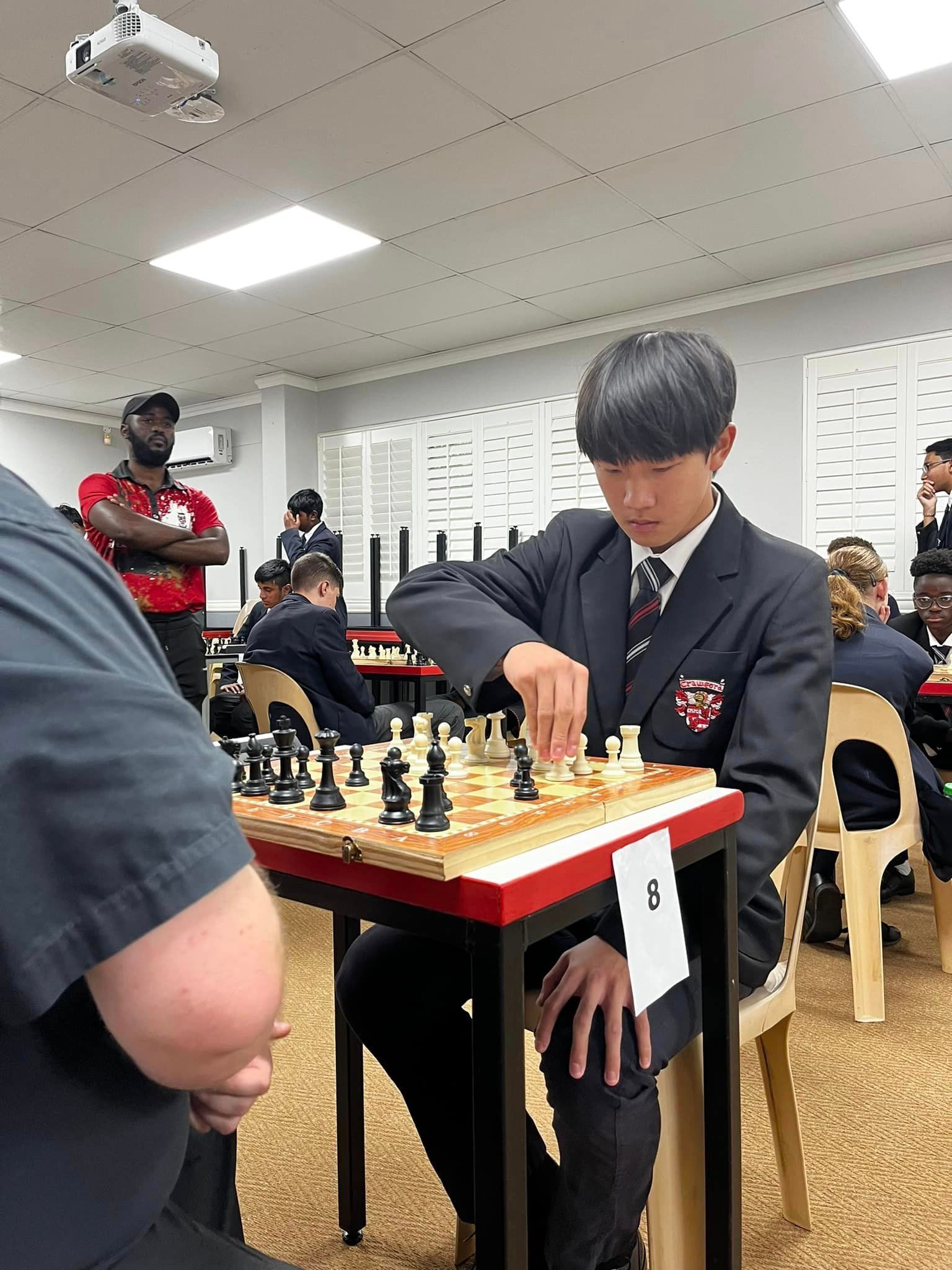 A man in a suit is sitting at a table playing chess.