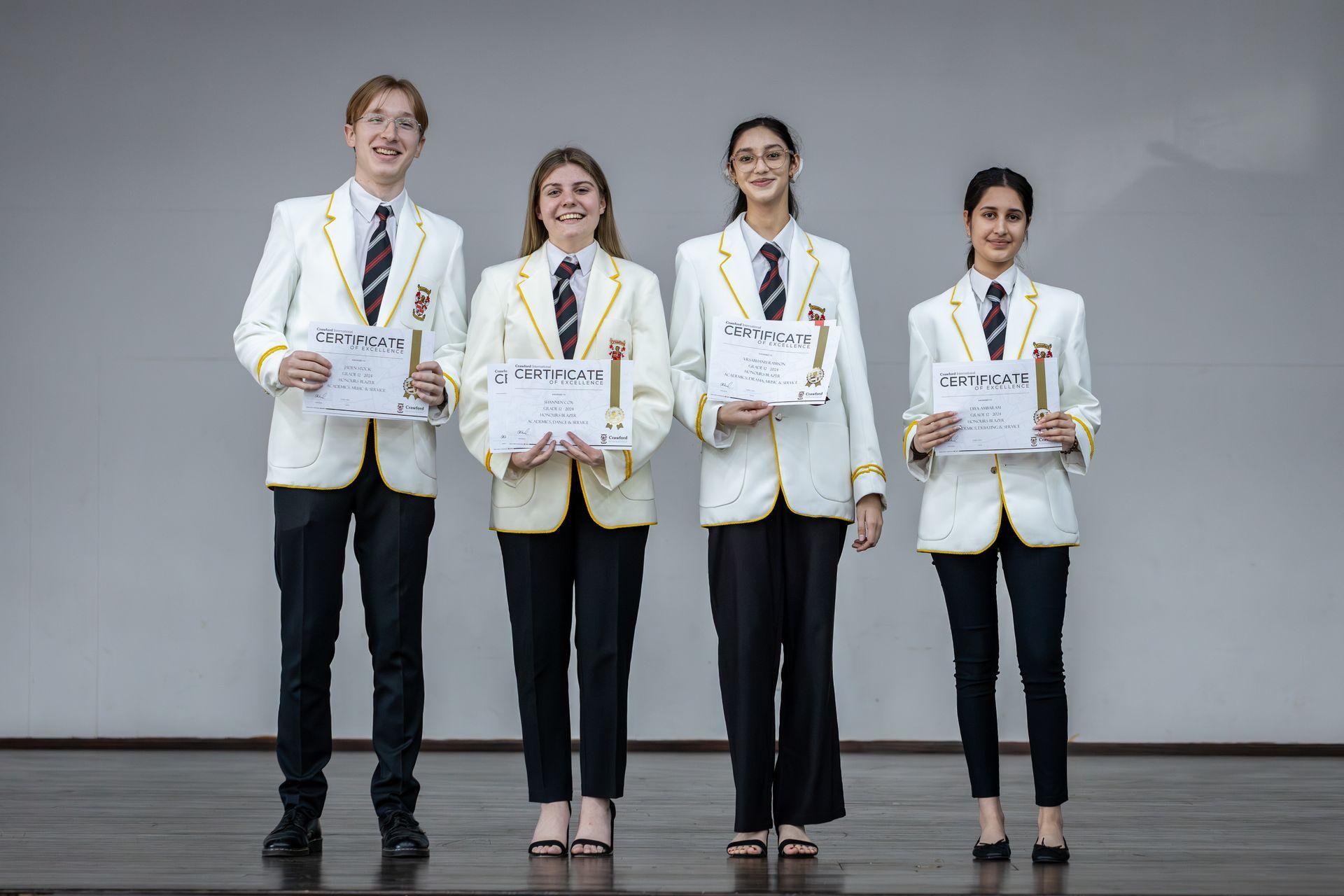 A group of young people are standing next to each other on a stage holding certificates.