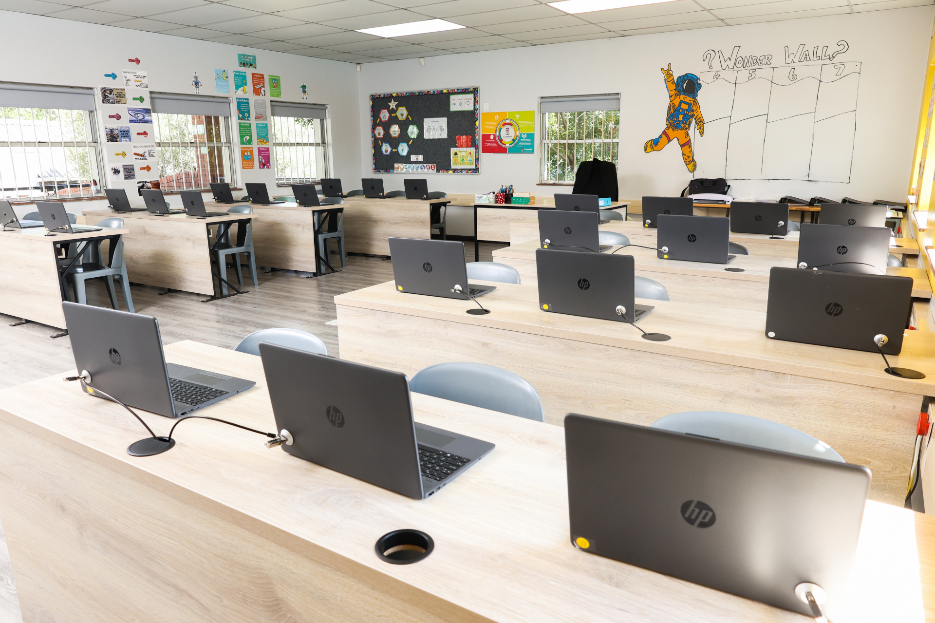 a row of laptops are sitting on a table and one of them says 12:10 on the screen