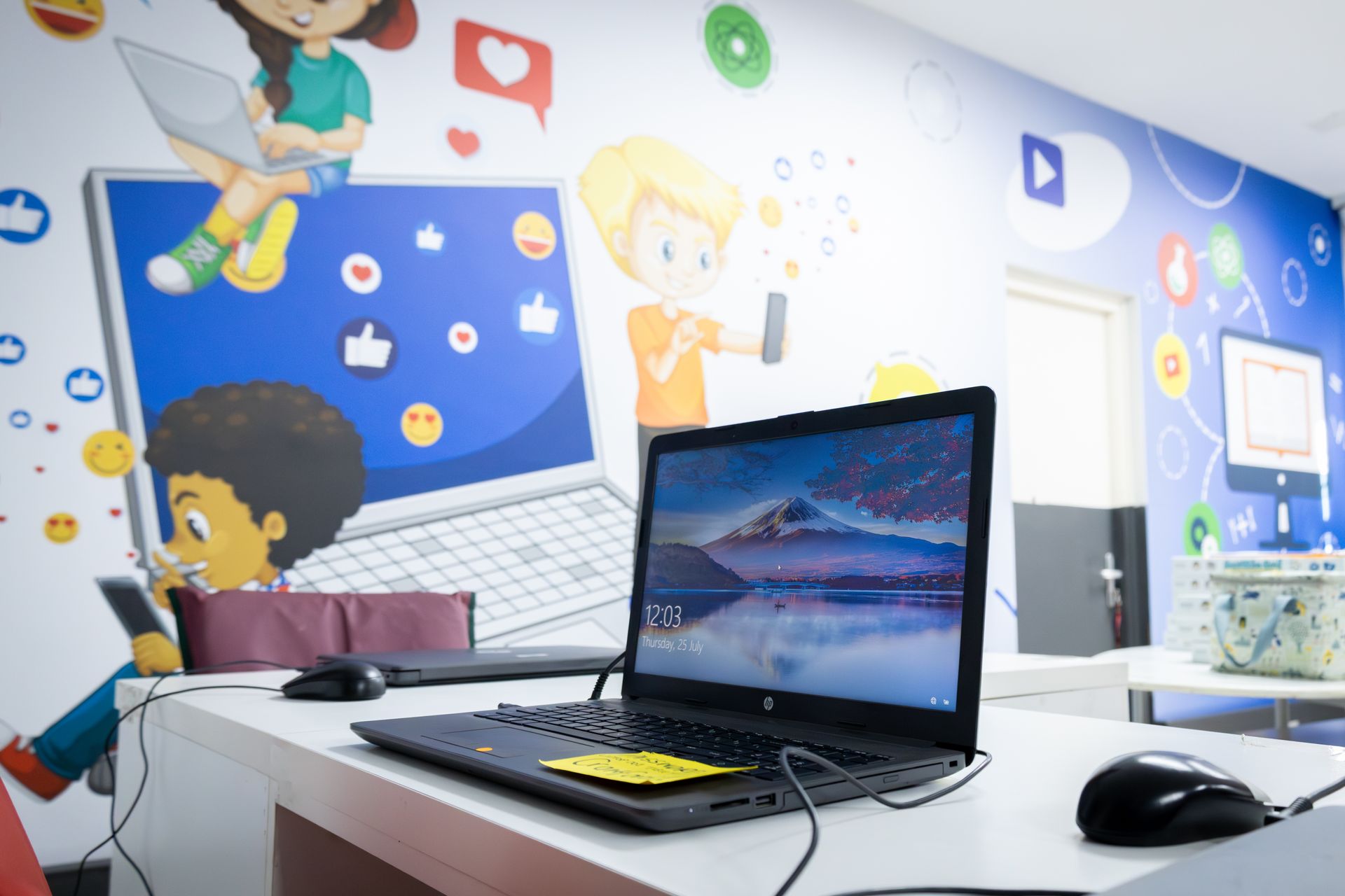 a row of laptops are sitting on a table and one of them says 12:10 on the screen