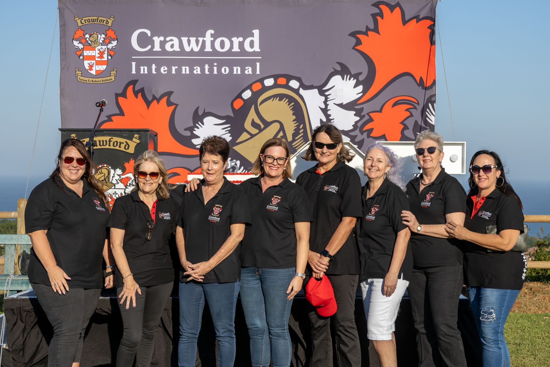 A group of women are posing for a picture in front of a crawford international sign.