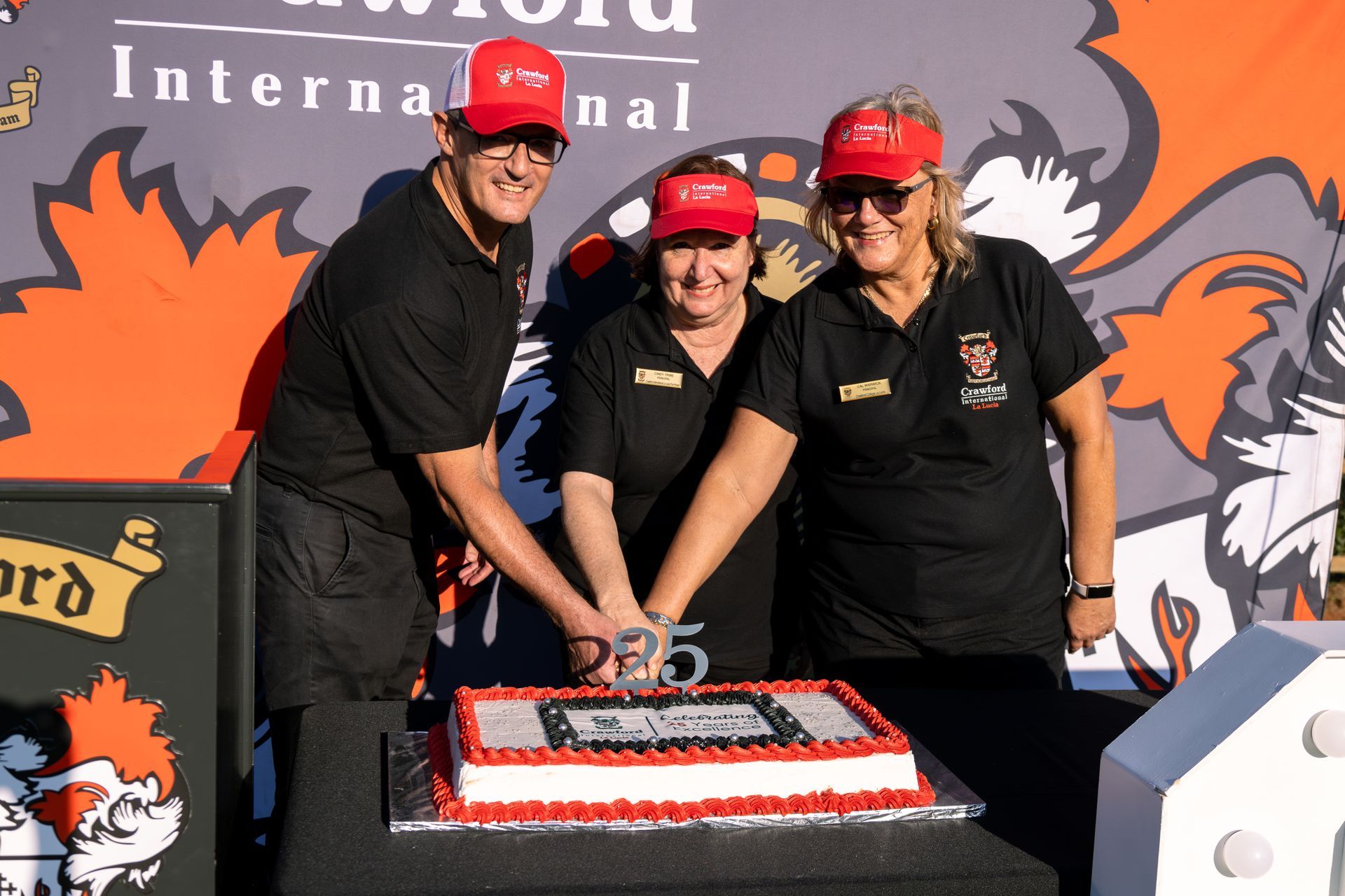 Three people are cutting a cake with the number 25 on it