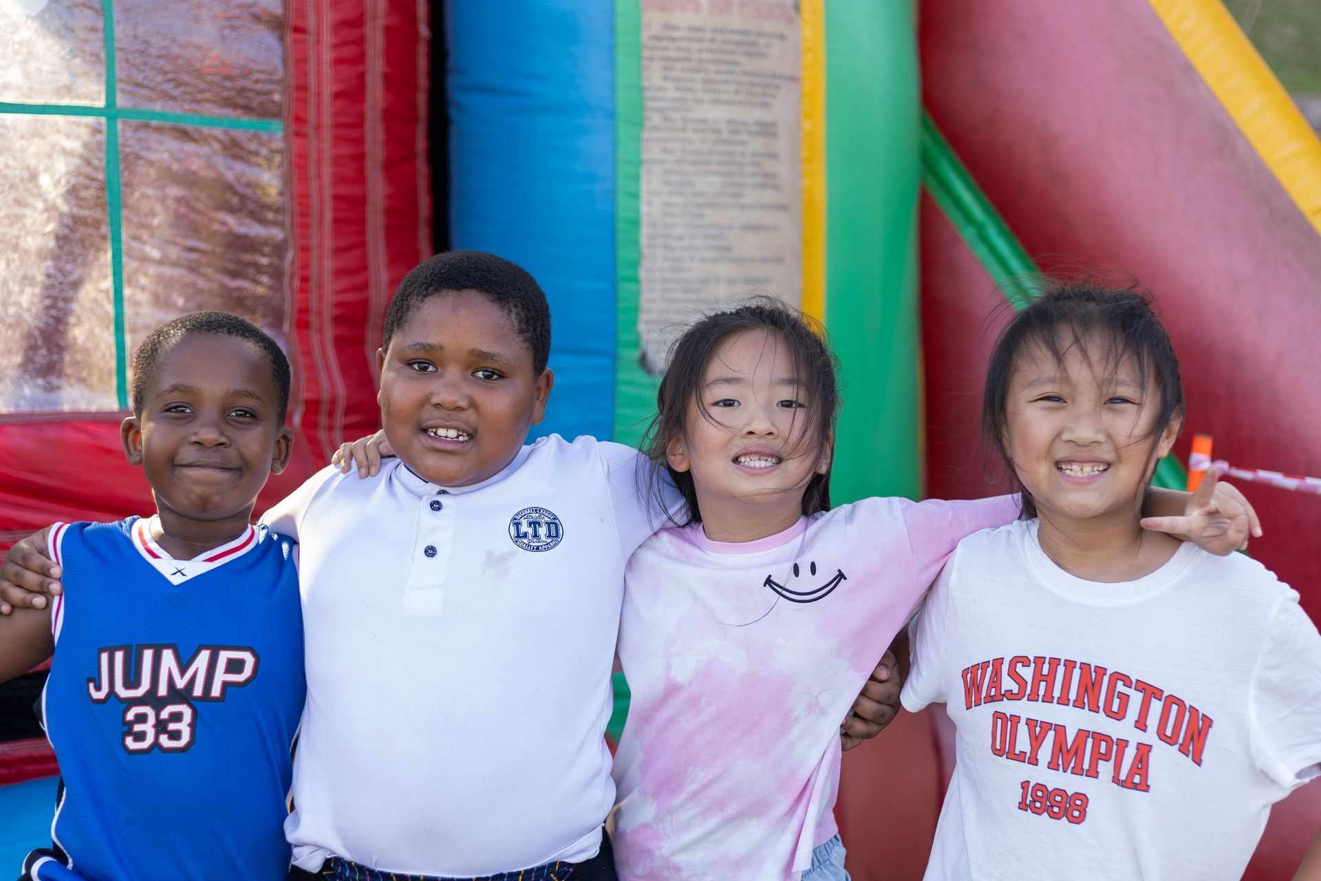 Four children posing for a picture with one wearing a washington olympia shirt
