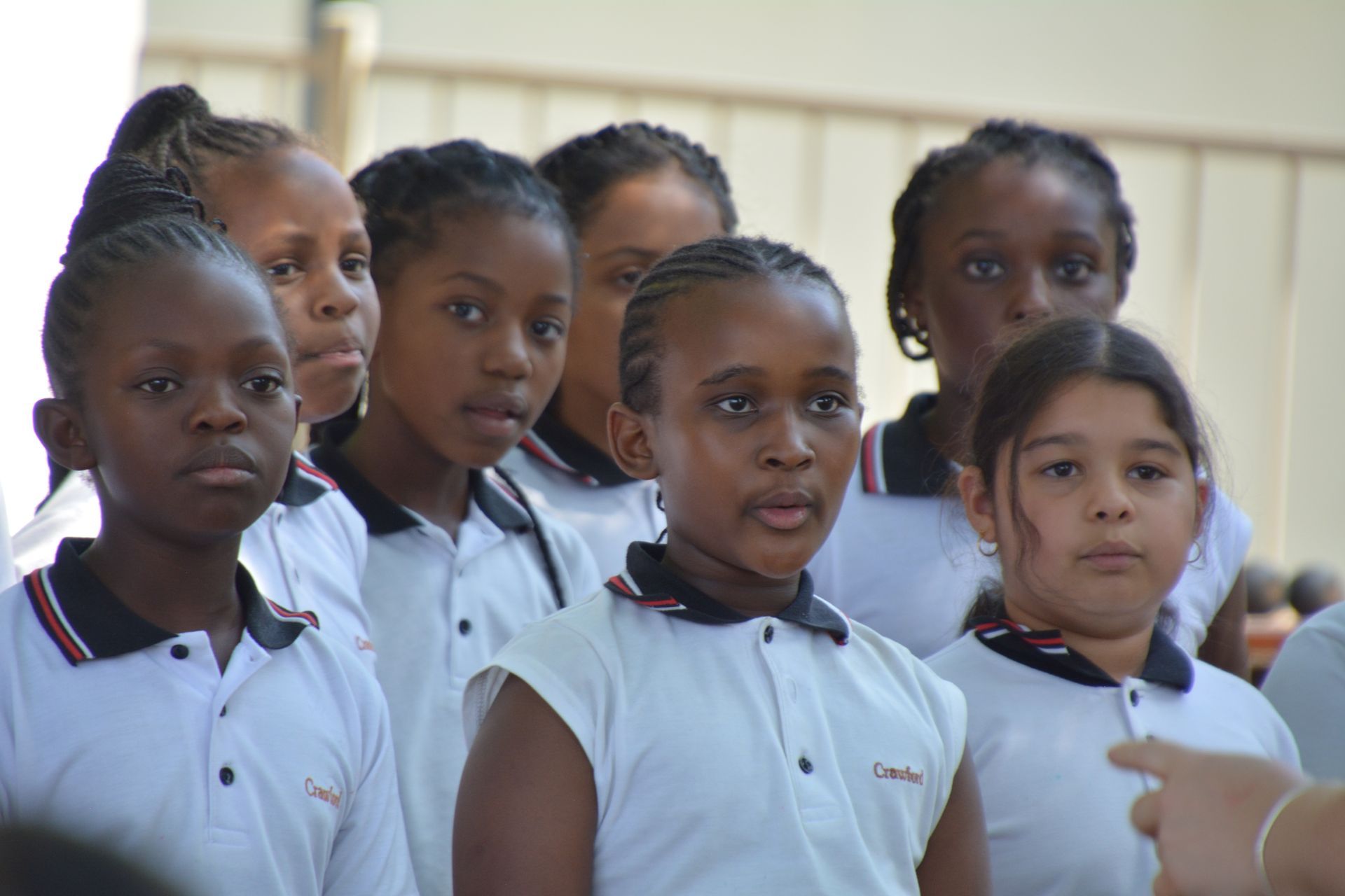A group of young girls in school uniforms are standing in a row.