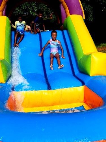 Children playing on a colorful inflatable water slide.