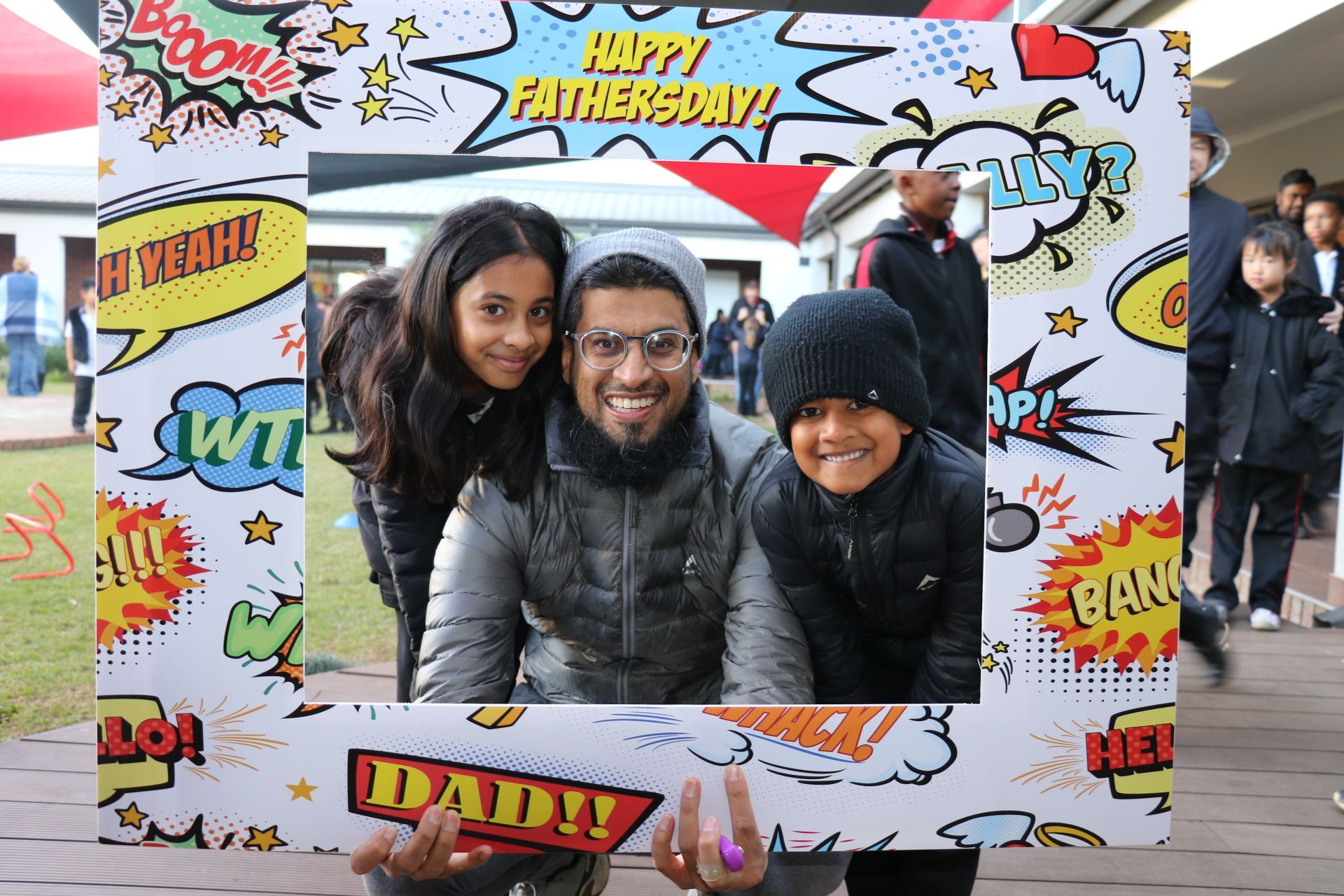 A man and two children are posing for a picture with a frame that says happy father 's day.
