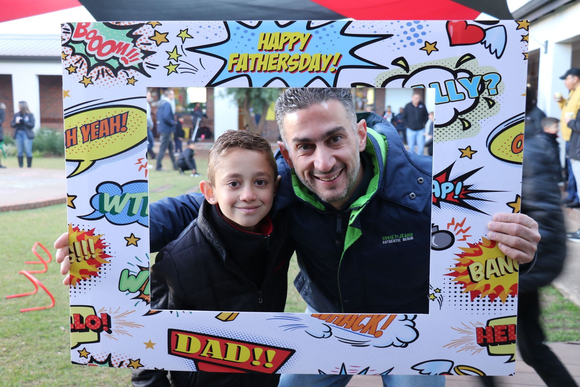 A man and a boy are posing for a picture with a frame that says happy fathers day.