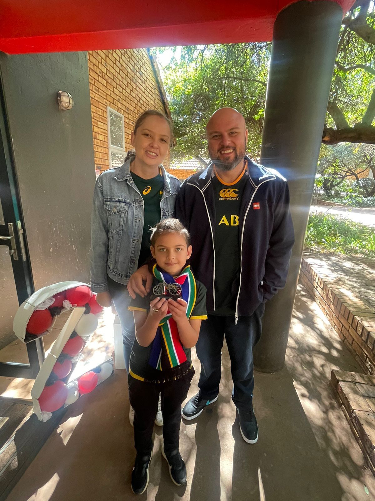 A man , woman and child are posing for a picture in front of a building.