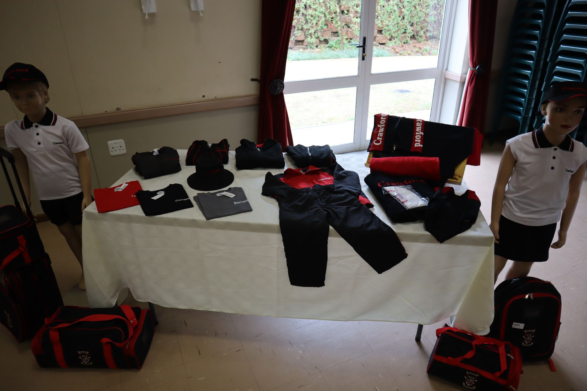 Two children are standing next to a table with clothes on it.