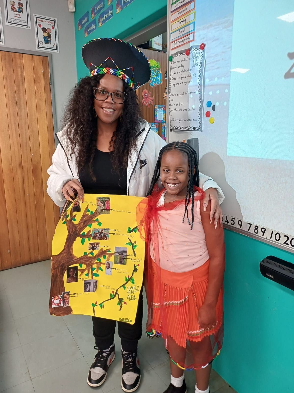 A woman and a girl are standing next to each other in a classroom holding a poster.