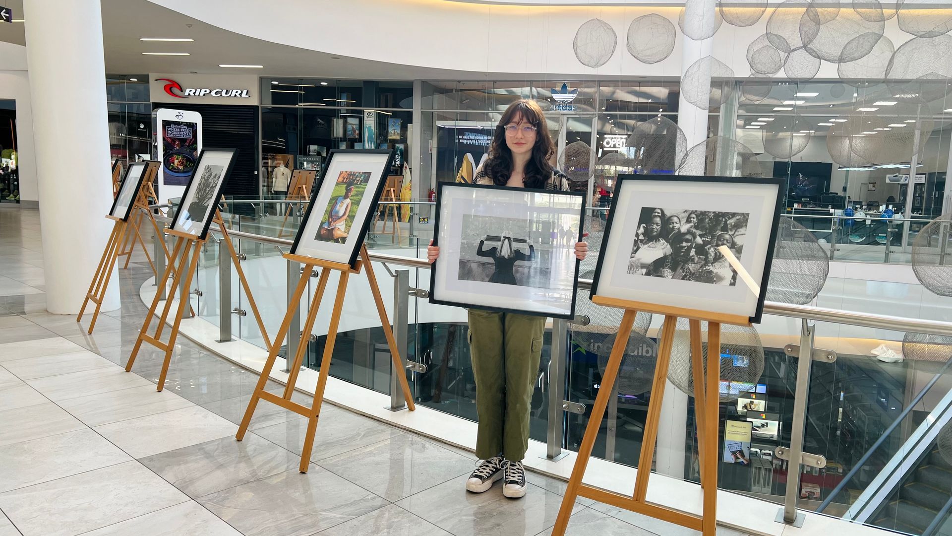 A woman is holding a framed picture in a mall.