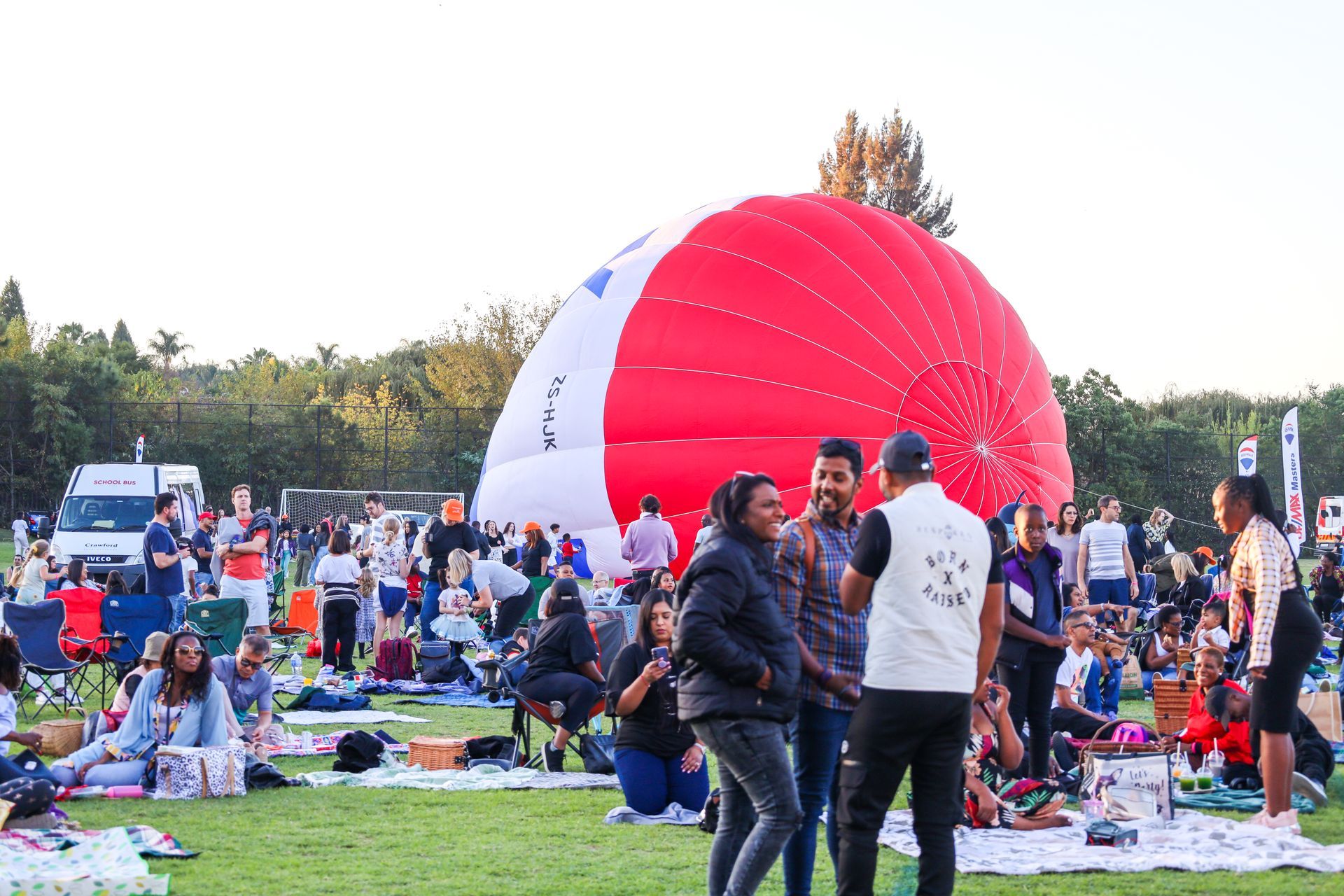 A group of people are standing around a large red and white hot air balloon.