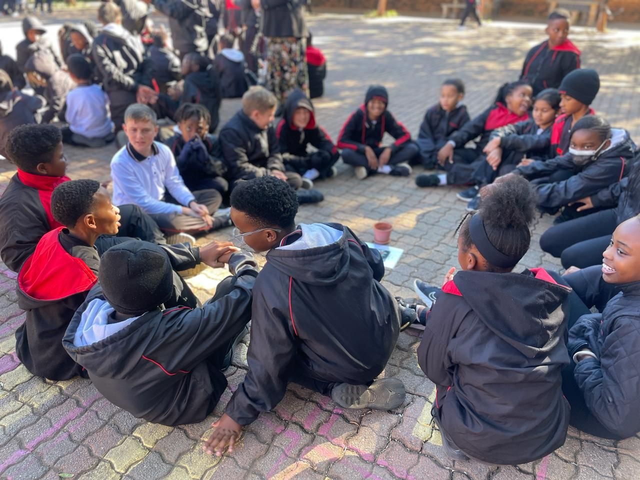 A group of children are sitting in a circle on the ground.