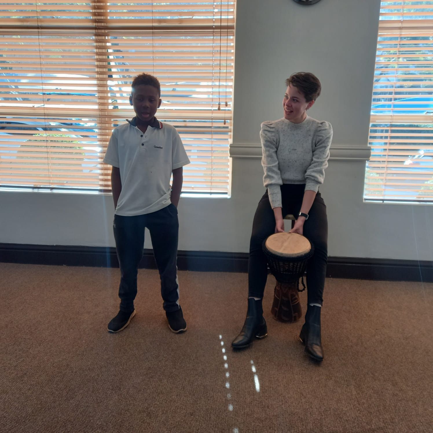 A woman is sitting on a drum next to a boy