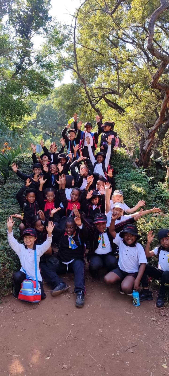 A group of children are posing for a picture in front of a tree.