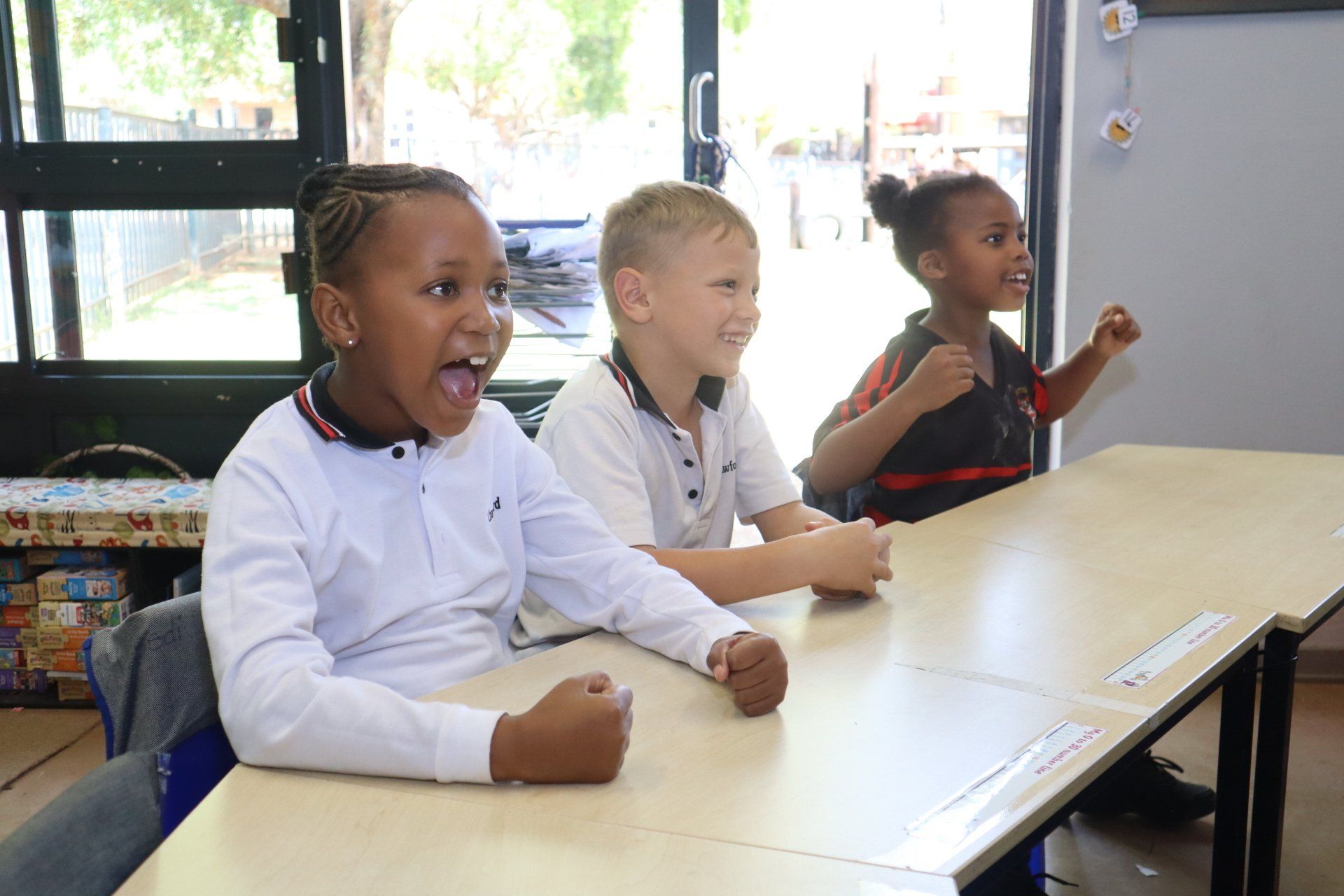 Three children are sitting at a table in a classroom.