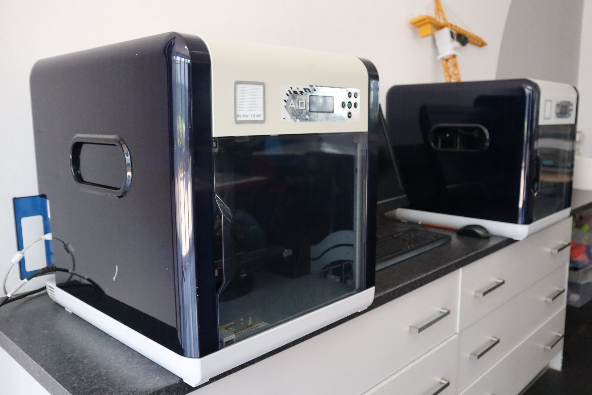 two 3d printers are sitting on a counter in a kitchen
