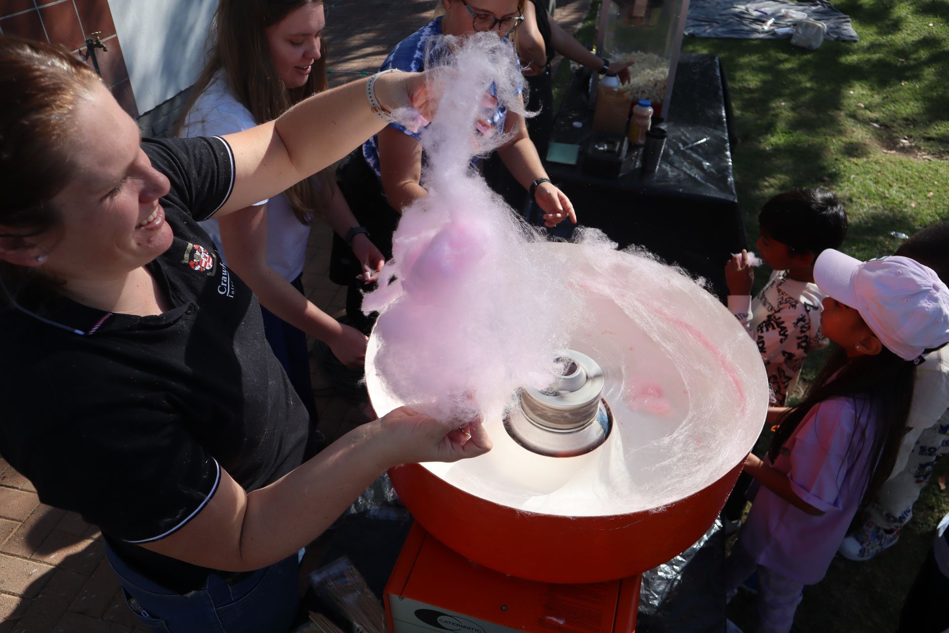 A woman is making cotton candy in a cotton candy machine.