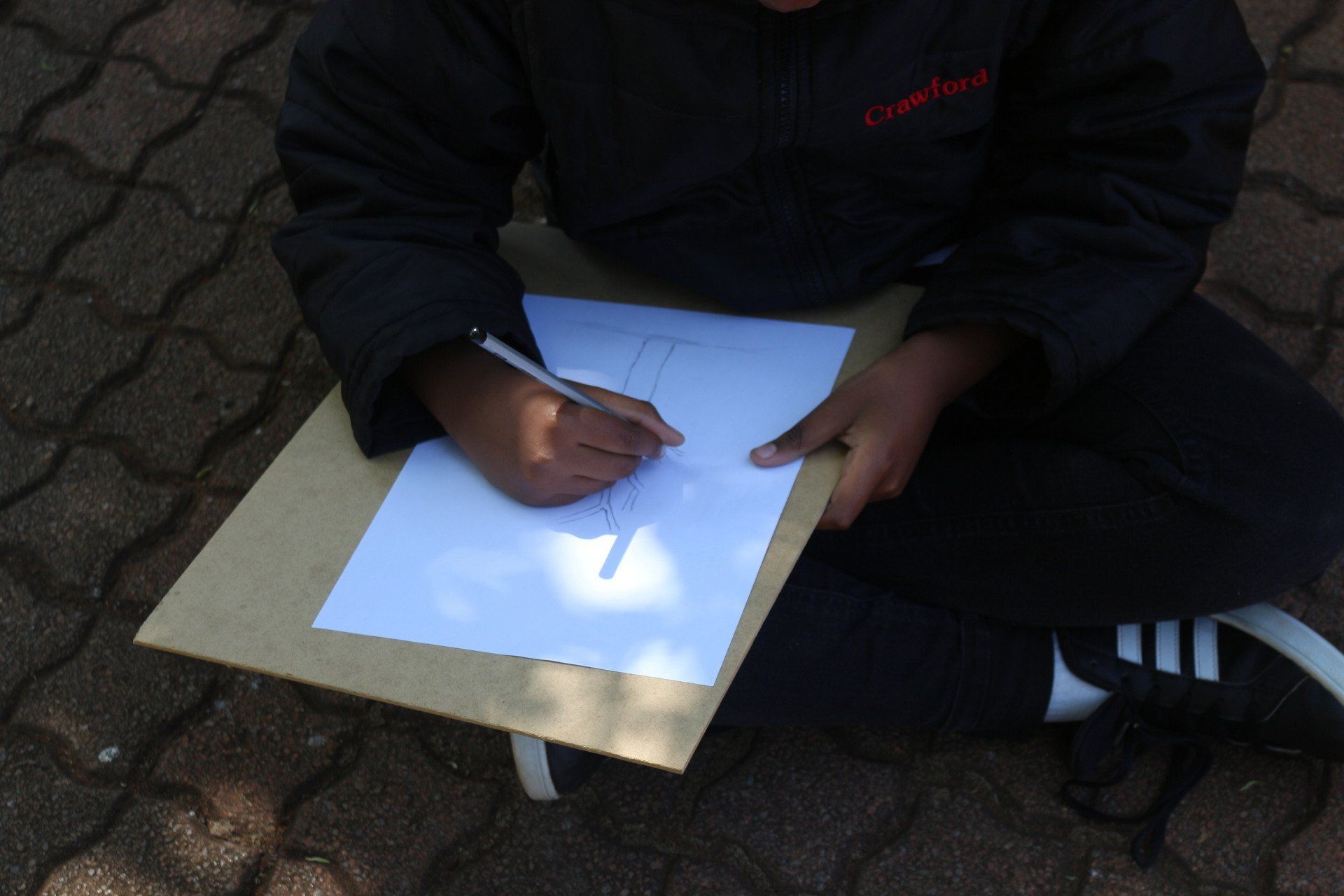 a person is sitting on the ground writing on a piece of paper