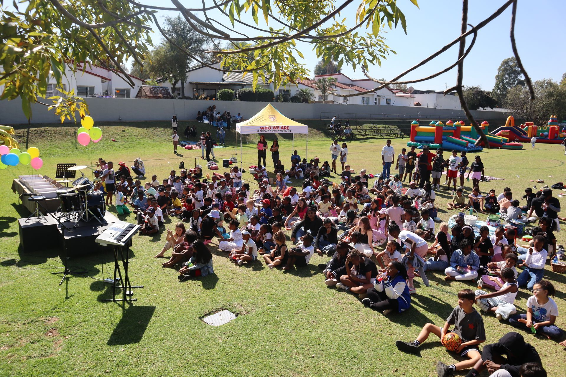 A large group of people are sitting on the grass in a park.