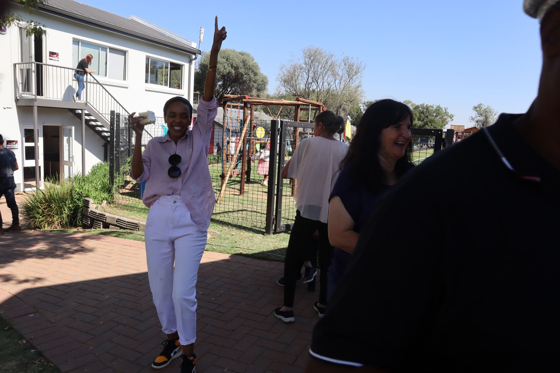 A woman in white pants is standing in front of a group of people.