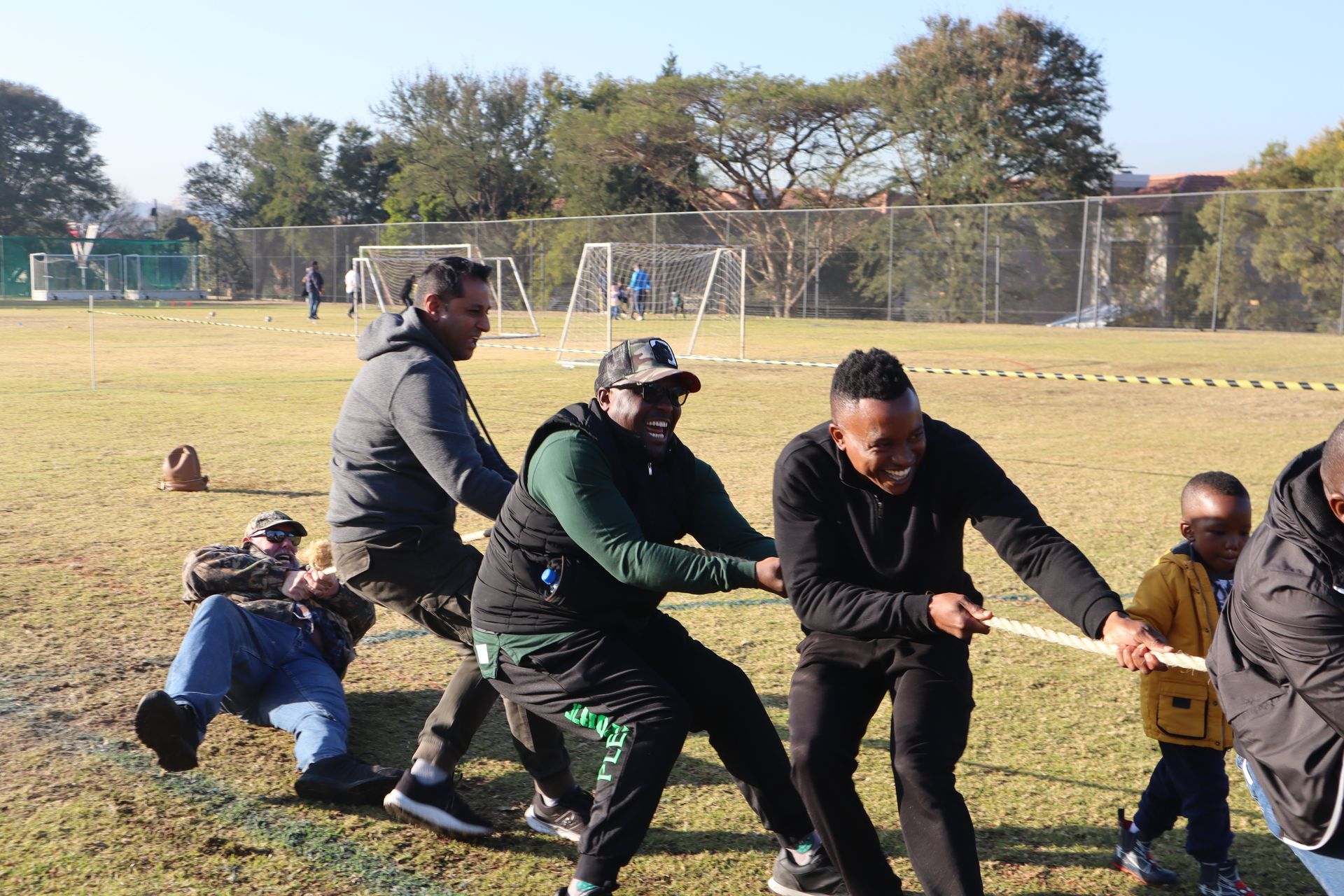A group of men are pulling a rope in a field.